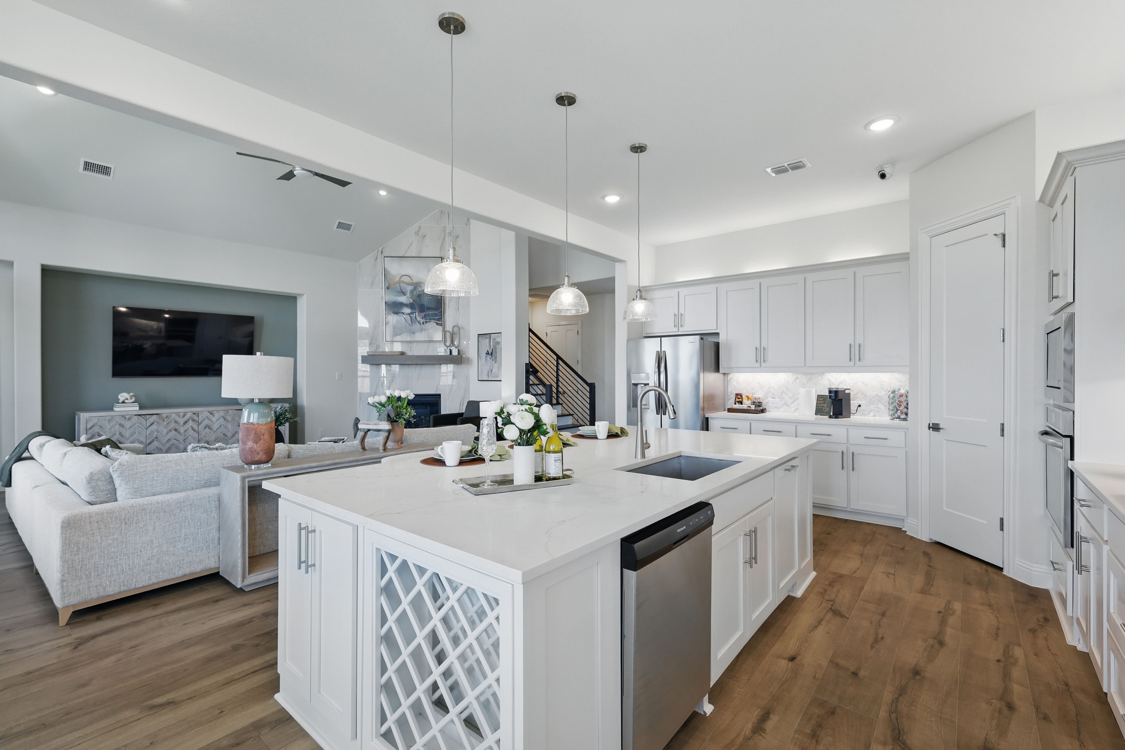 Modern kitchen and living area with white cabinets, marble island, stainless appliances in Rio Vista at Kelly Ranch.
