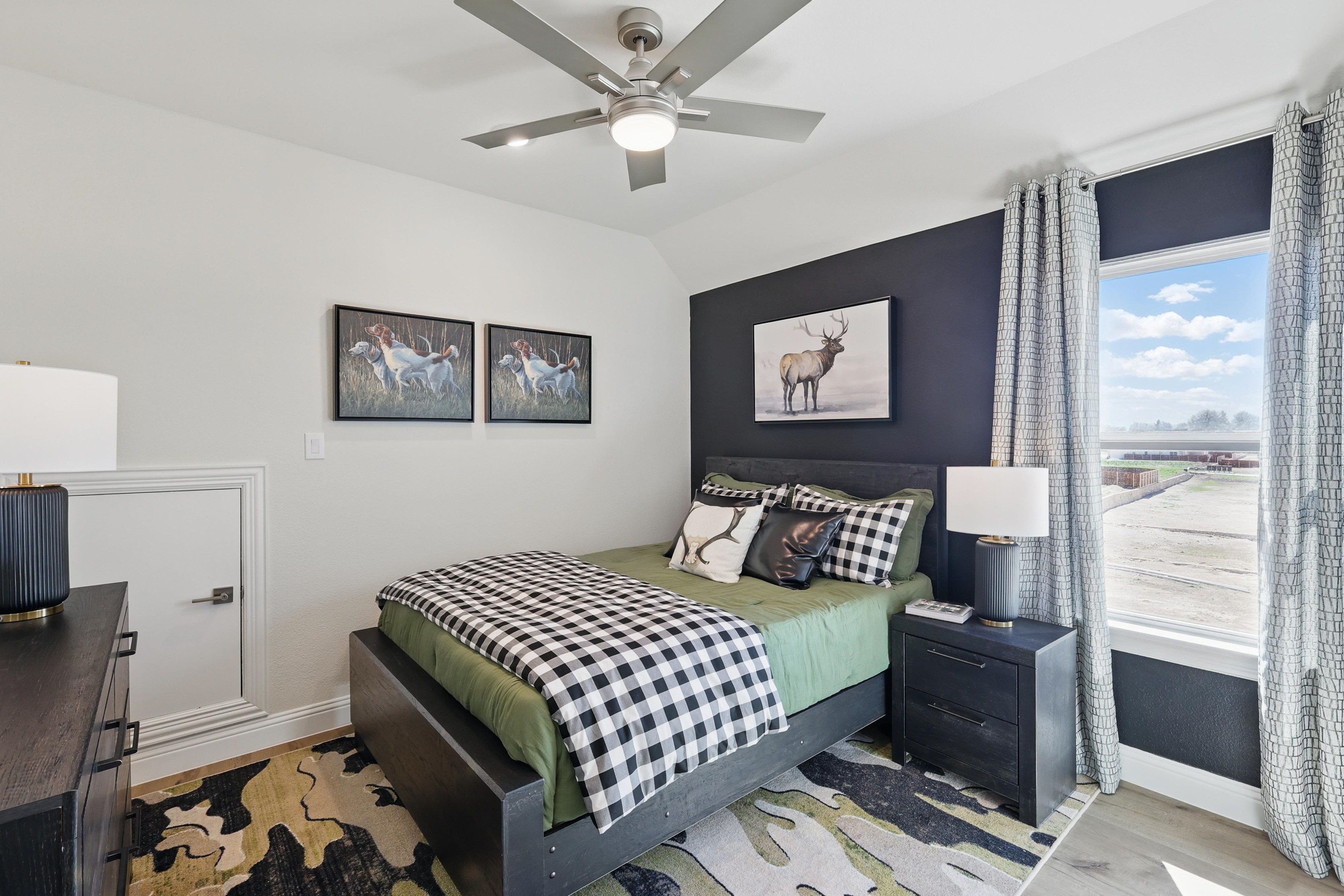 Bedroom with black accent wall, plaid bedding, animal artwork, large window view at Kelly Ranch, Rio Vista.