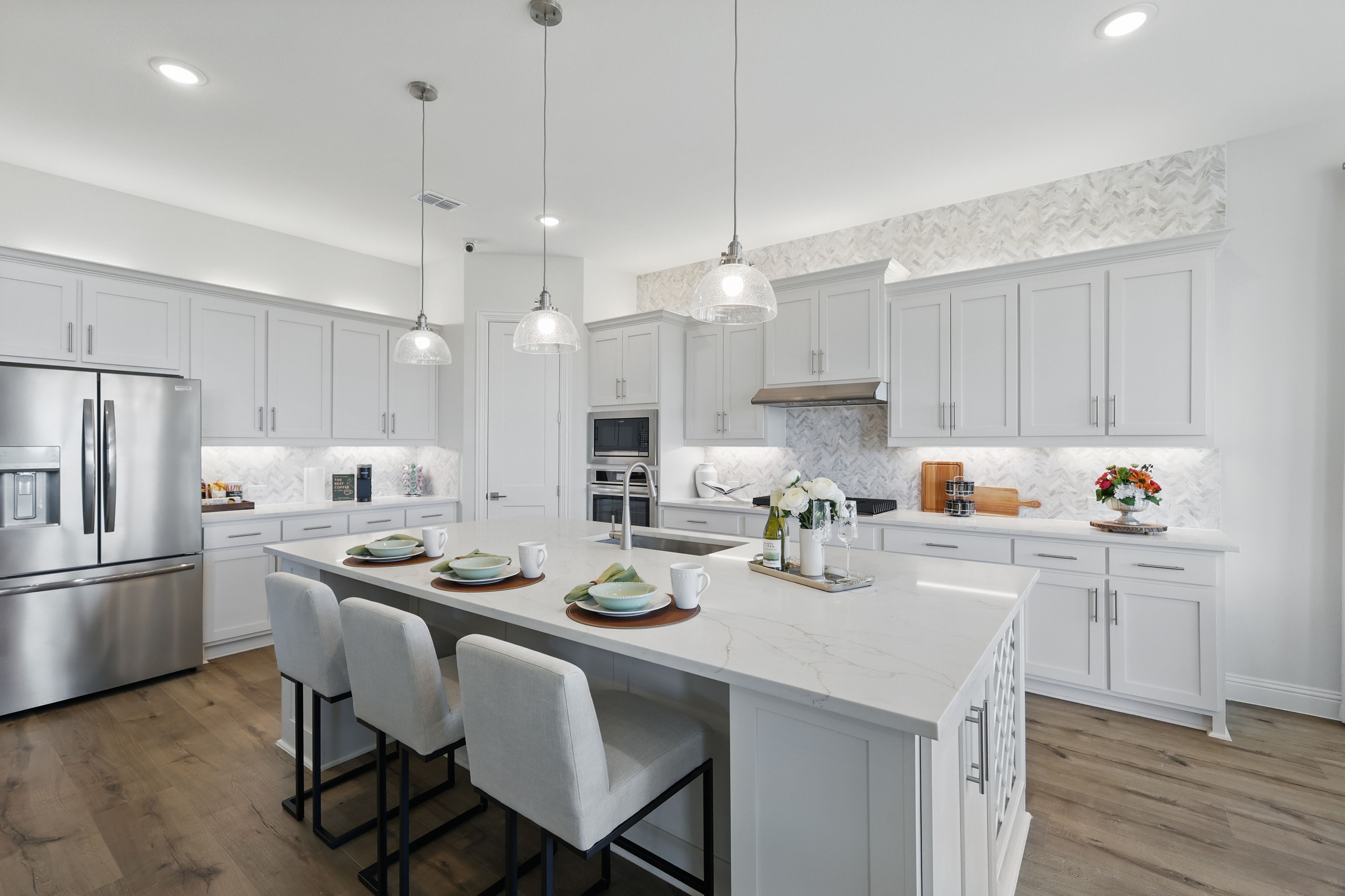 Modern kitchen with white cabinets, marble island, pendant lights in Rio Vista at Kelly Ranch, hardwood floor.