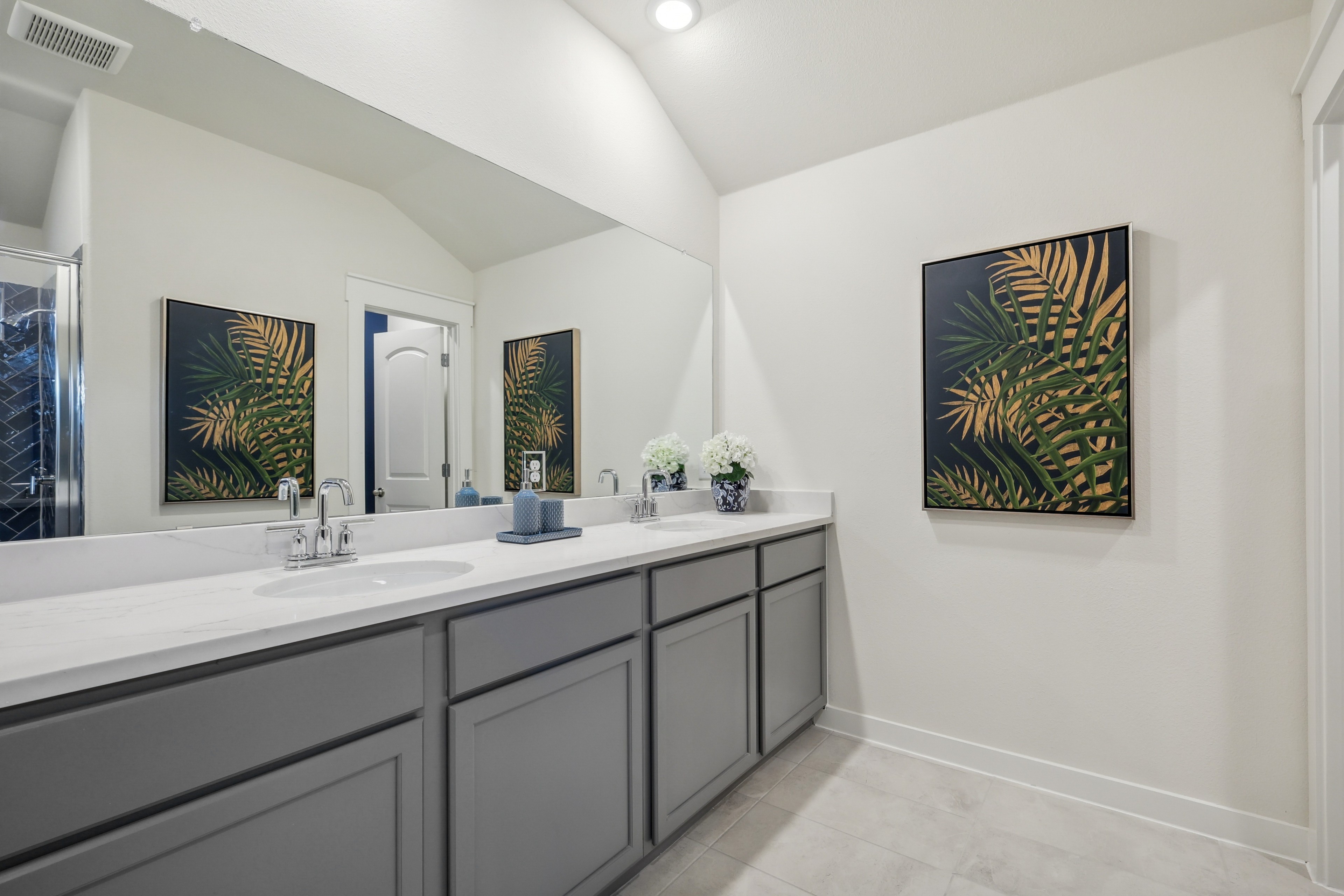 Sleek modern bathroom with large mirror, dual sinks, gray cabinets, Palm Springs decor in Churchill community.