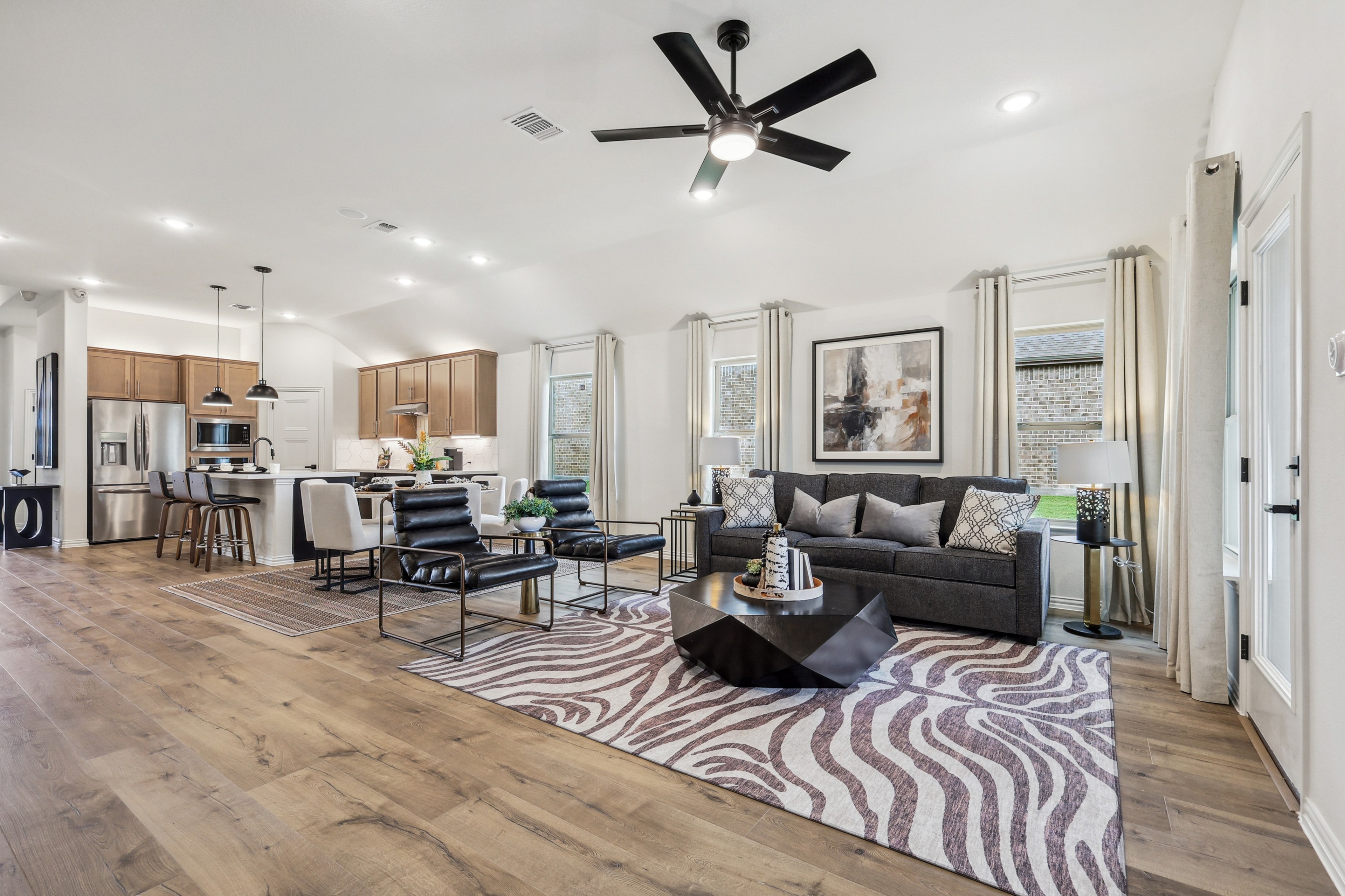 Modern open-plan living room with elegant furnishings, high ceiling, and wood flooring in Churchill community.