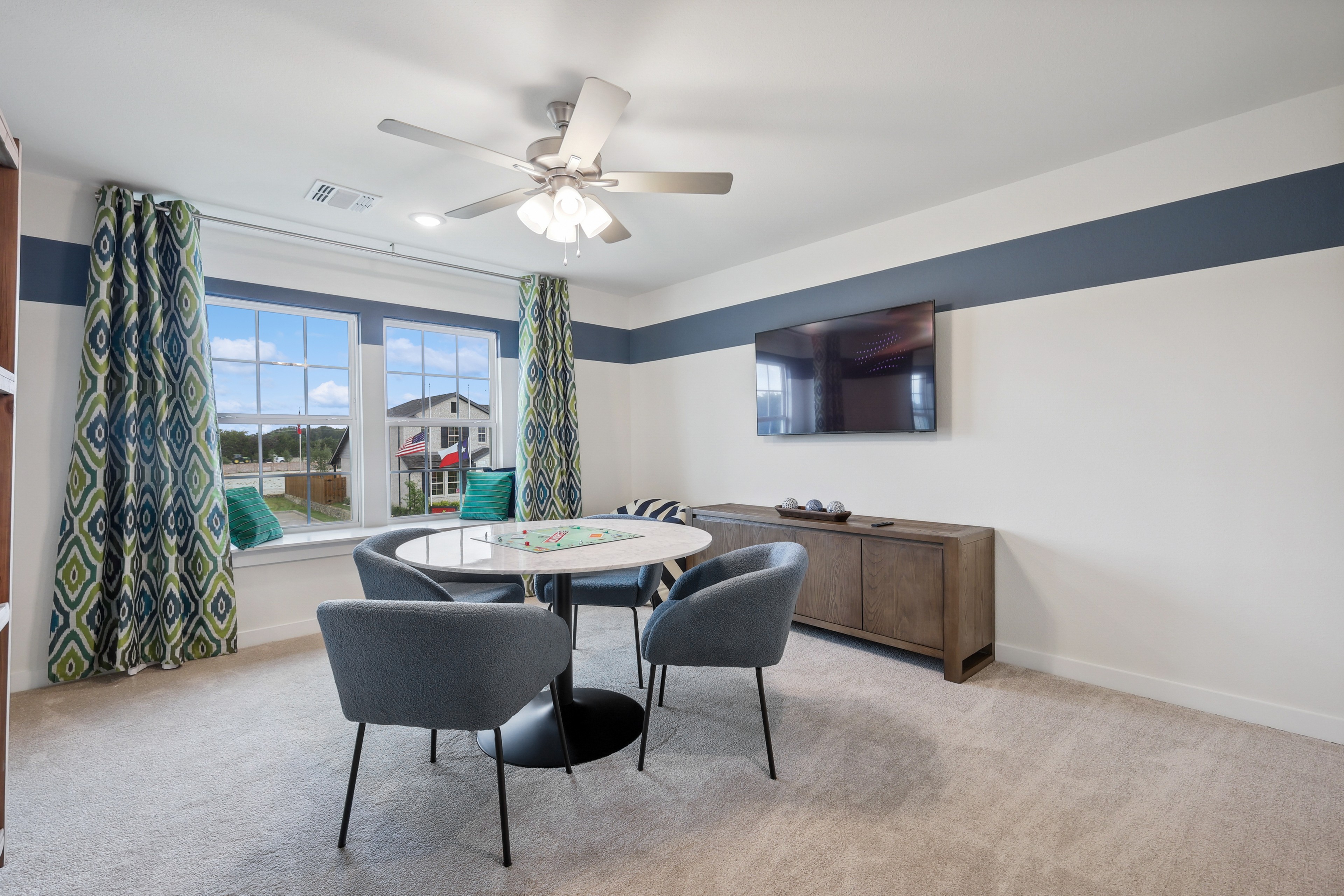 Modern living area with large windows, elegant drapes, round table, plush chairs in Churchill community.