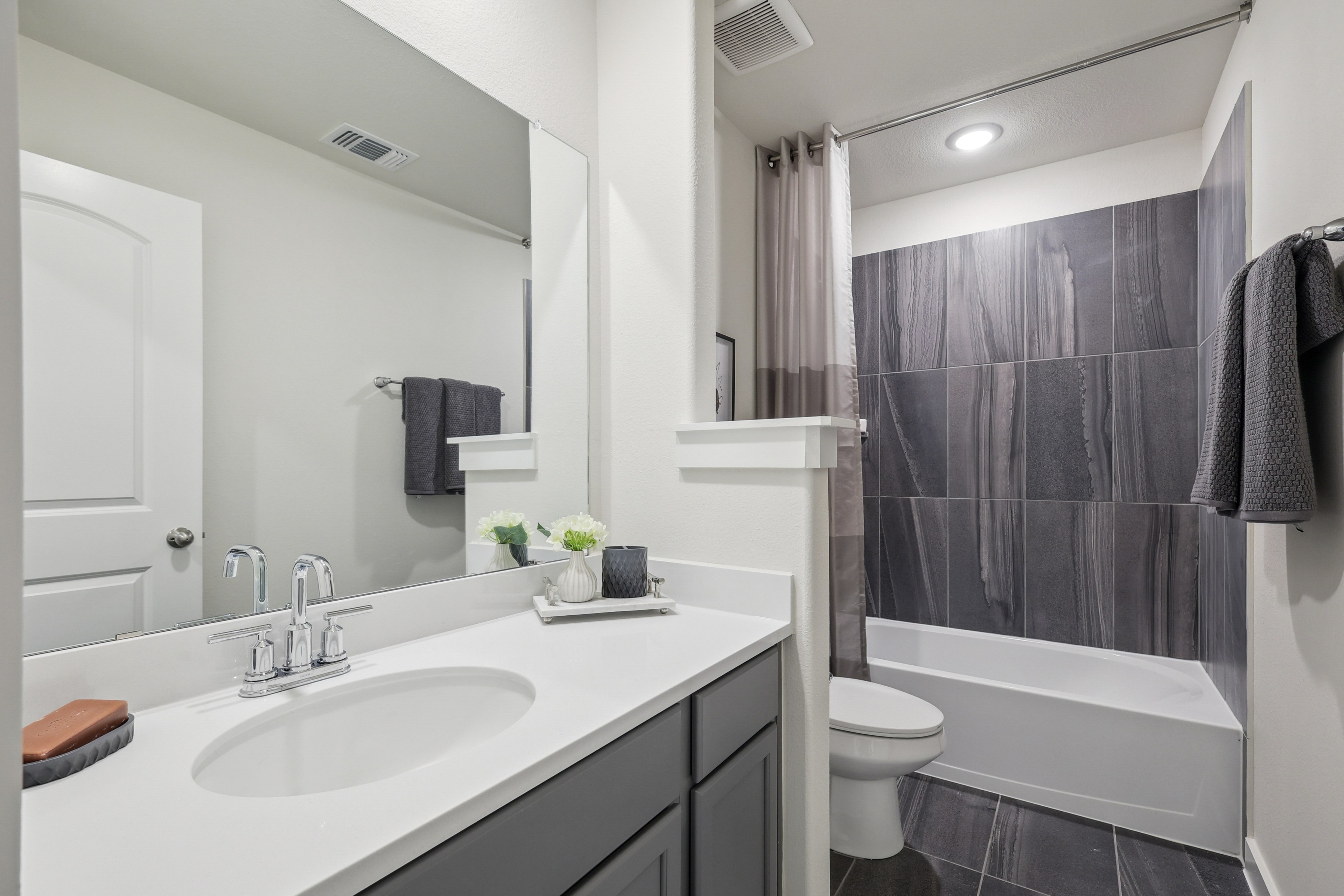 Modern bathroom with sleek black tiles, white countertop, and elegant fixtures. Located in Churchill community.
