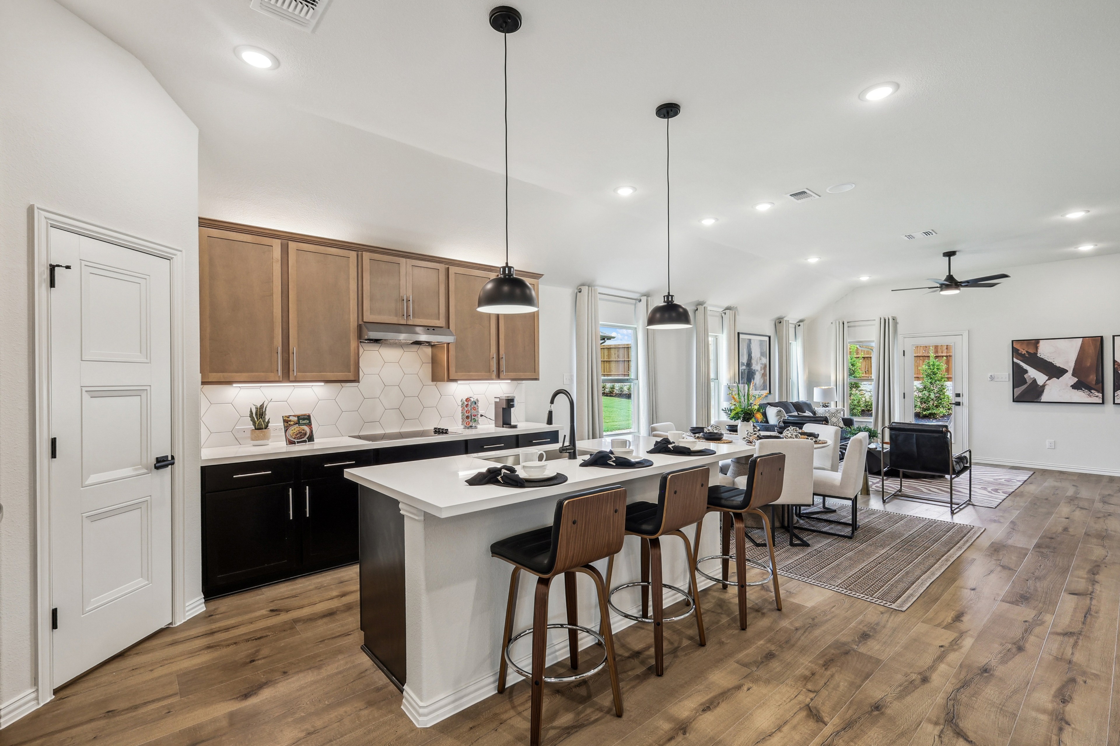 Modern kitchen in Churchill, wood floors, hex tiles, island seating; open plan with living area.