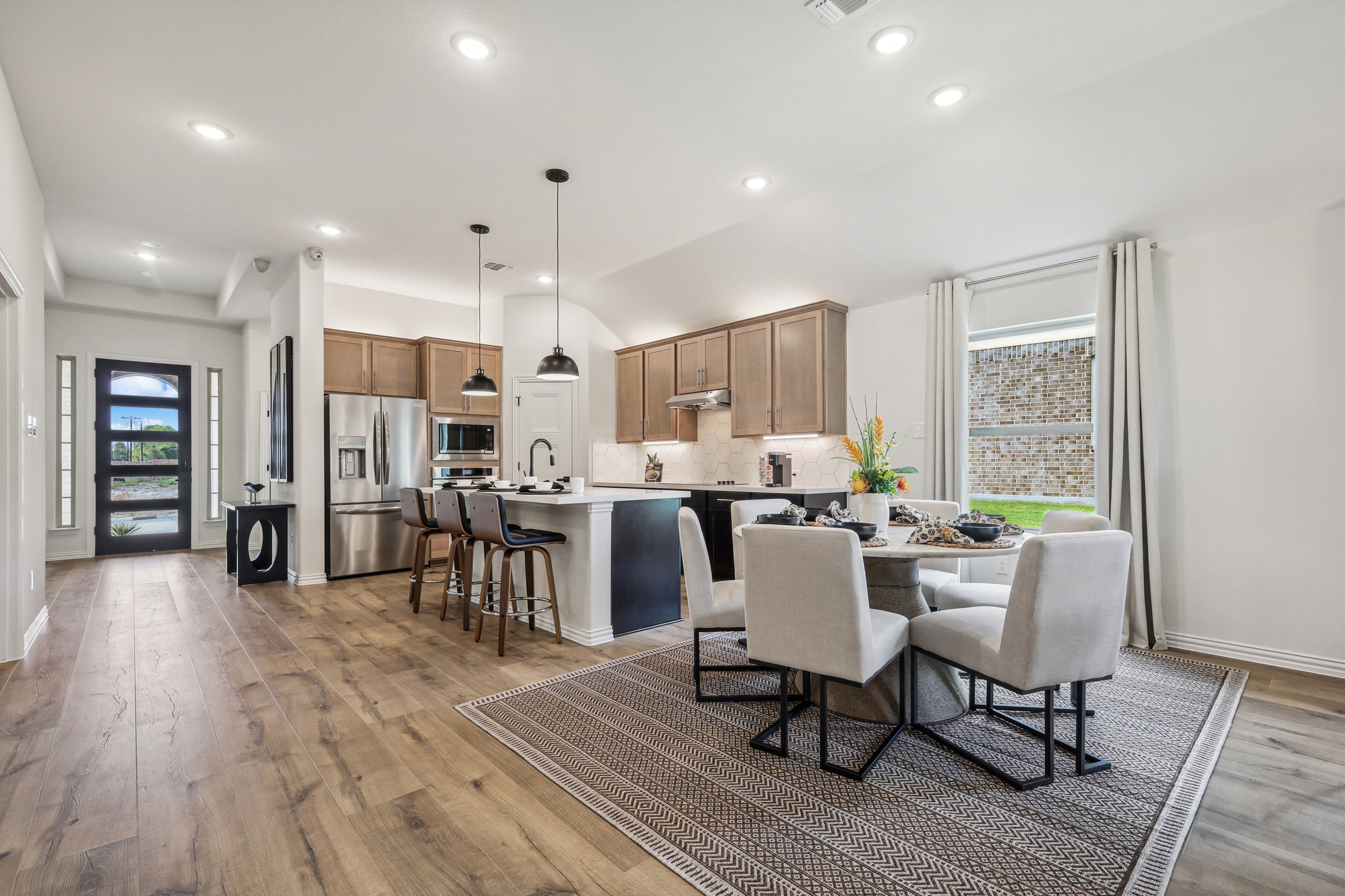 Modern kitchen in Churchill with island, pendant lights, wood floors, and dining area. Bright, open layout enhances space.