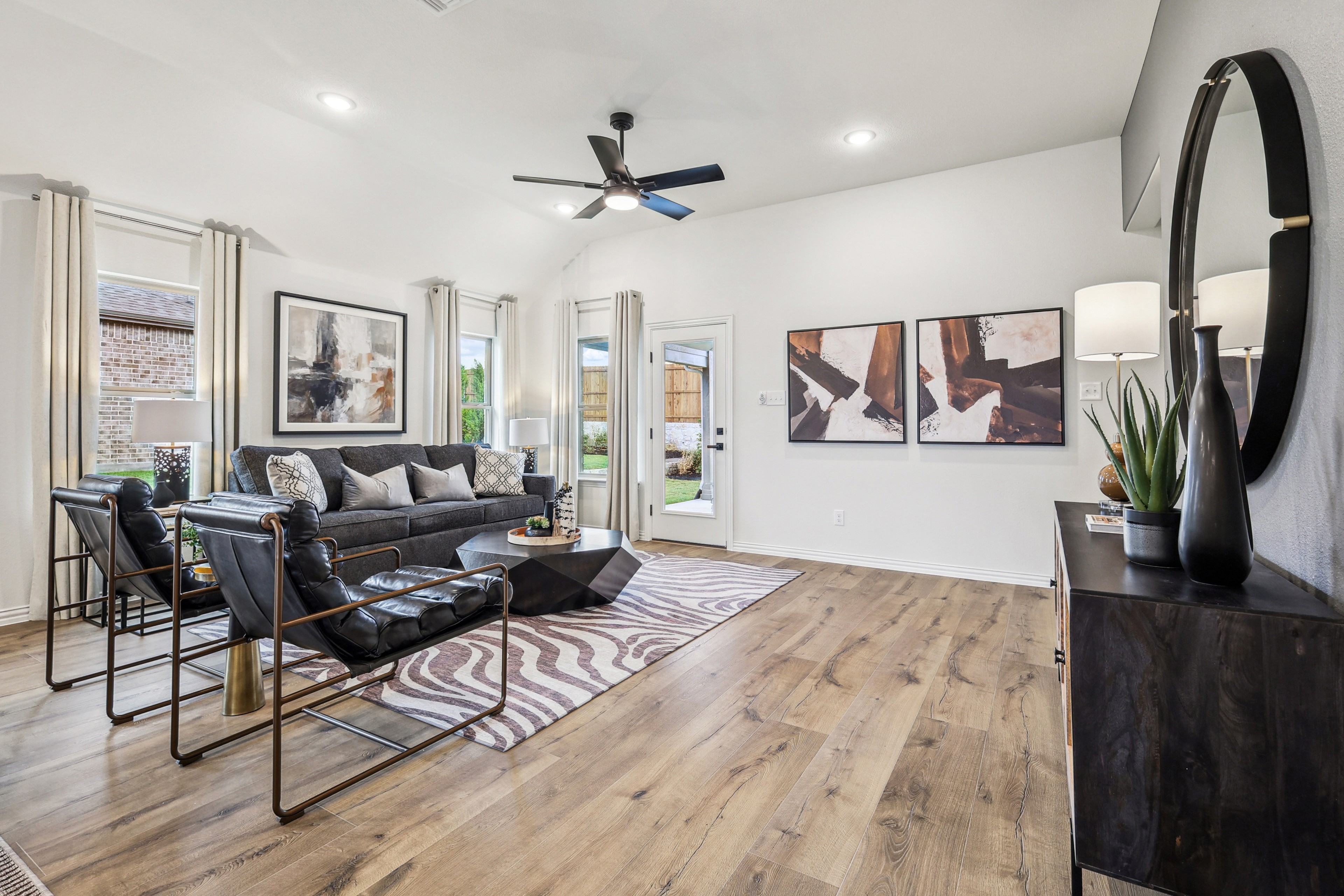 Spacious Churchill living room with modern furniture, wood flooring, abstract art, and large windows.