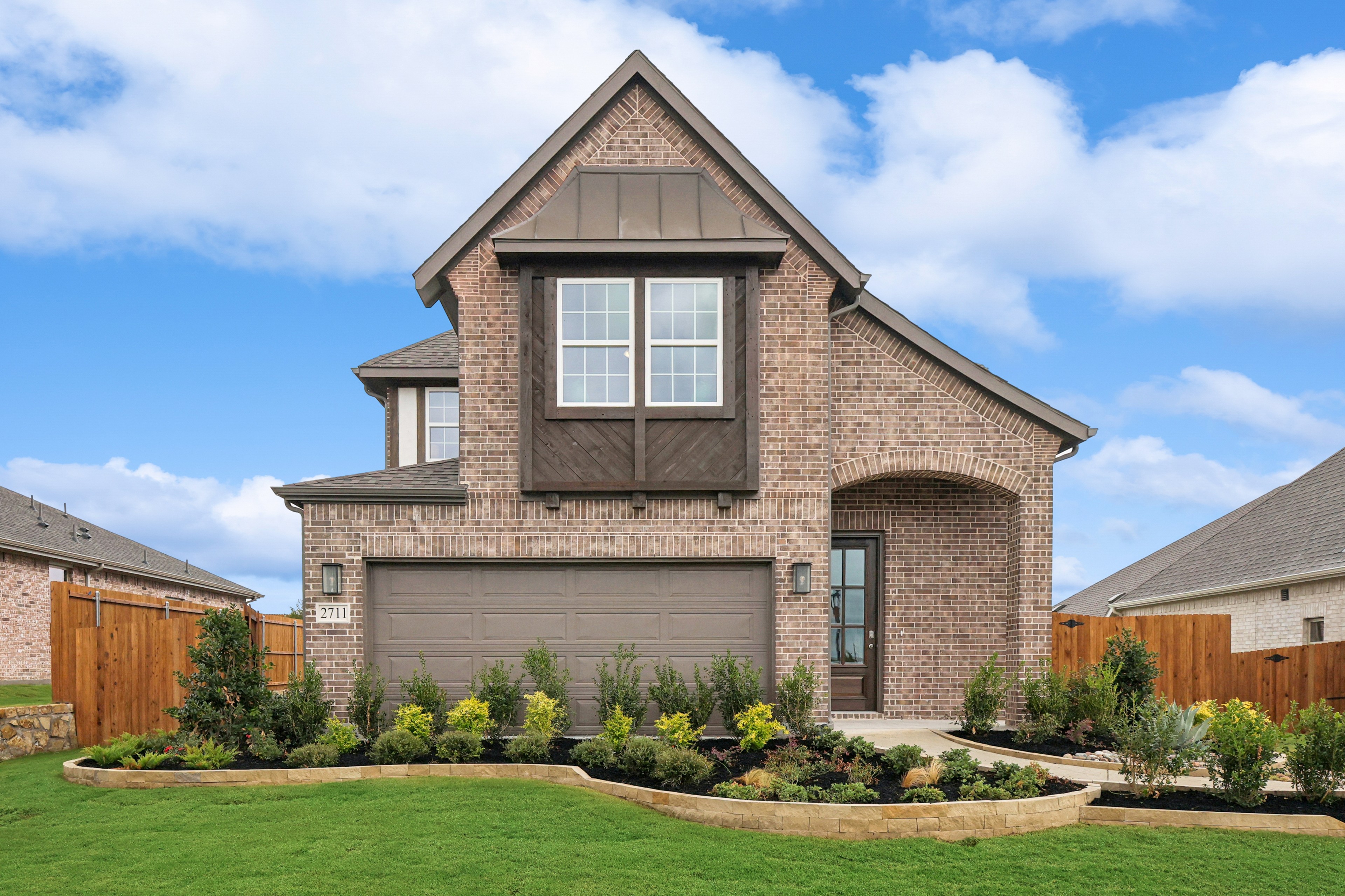 Elegant brick house with gable roof, lush landscaping, in Churchill community's suburban setting.