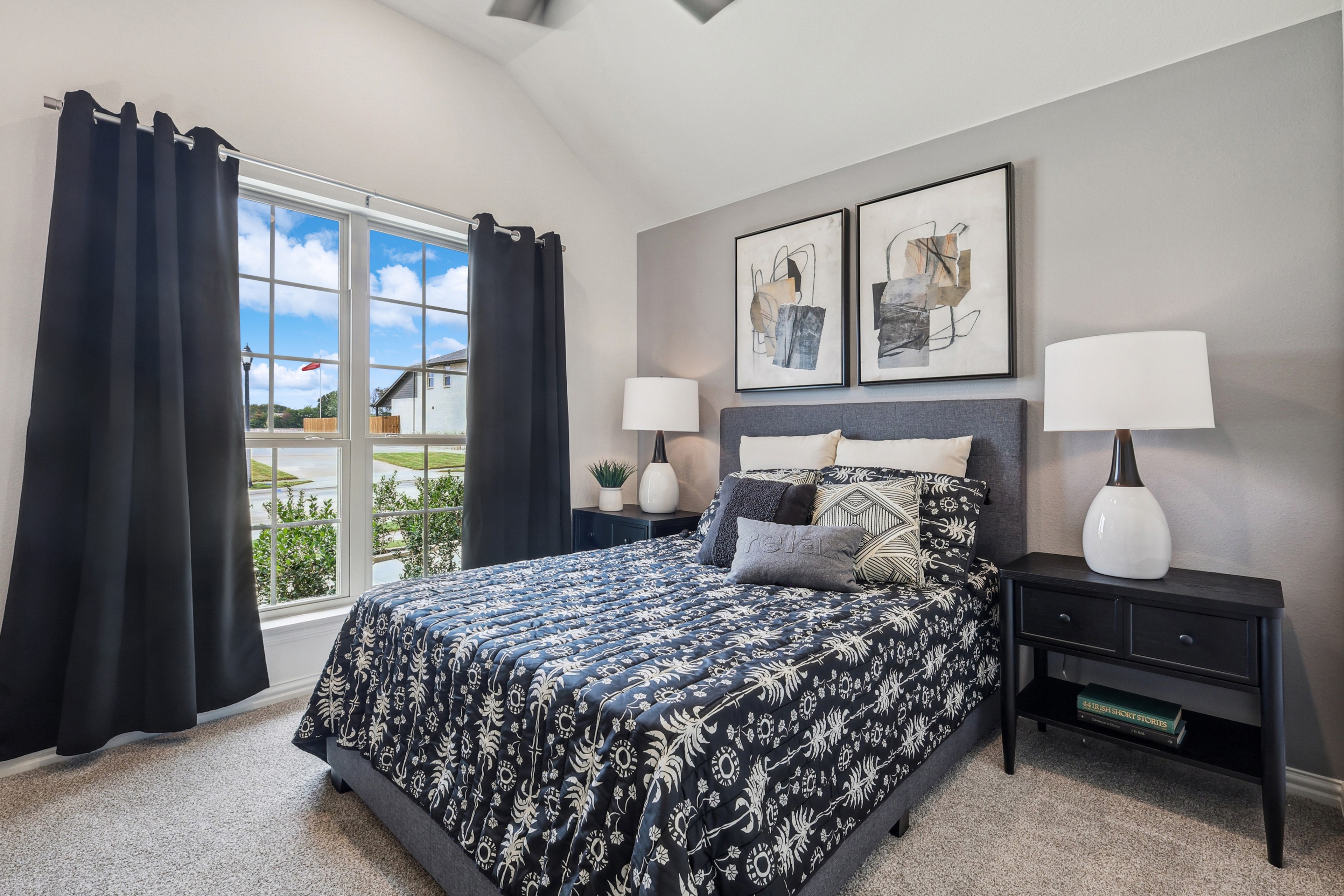 Elegant bedroom with large window, modern art, and plush bedding in Churchill community, lit by natural light.