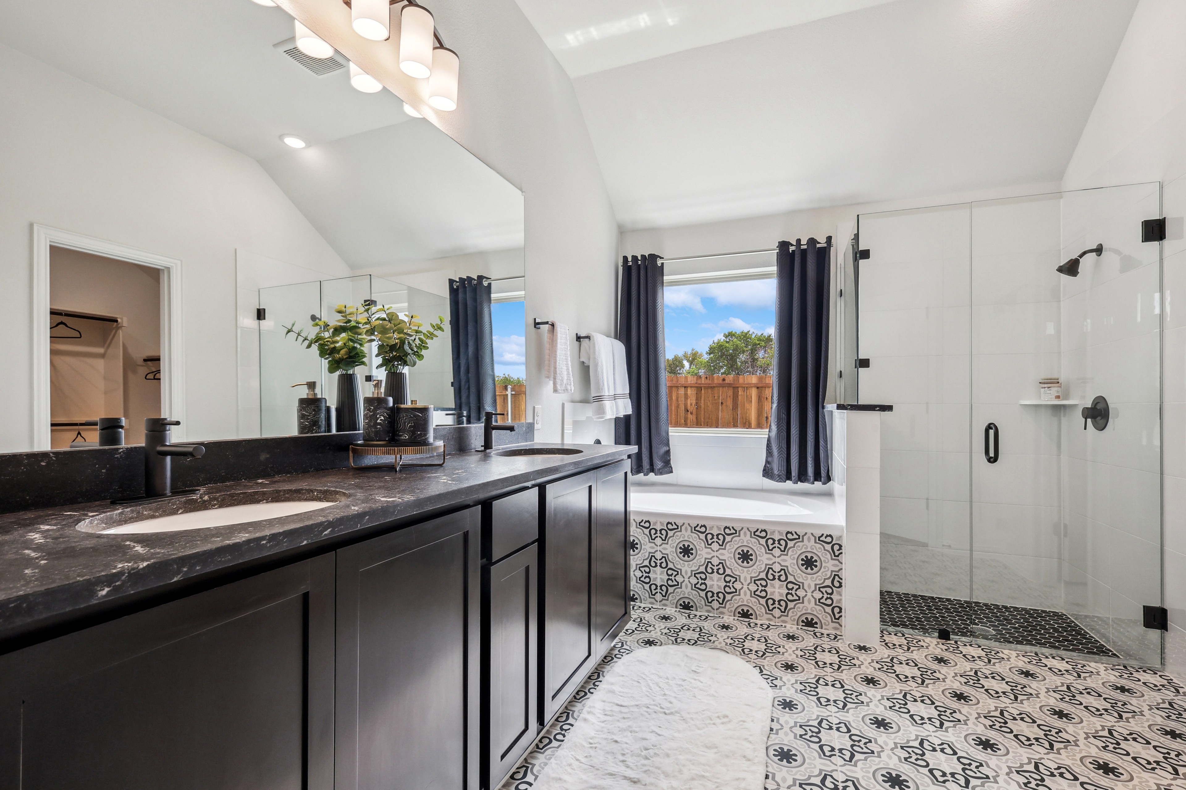 Luxurious bathroom with black marble vanity, patterned floor, glass shower, in Churchill community.