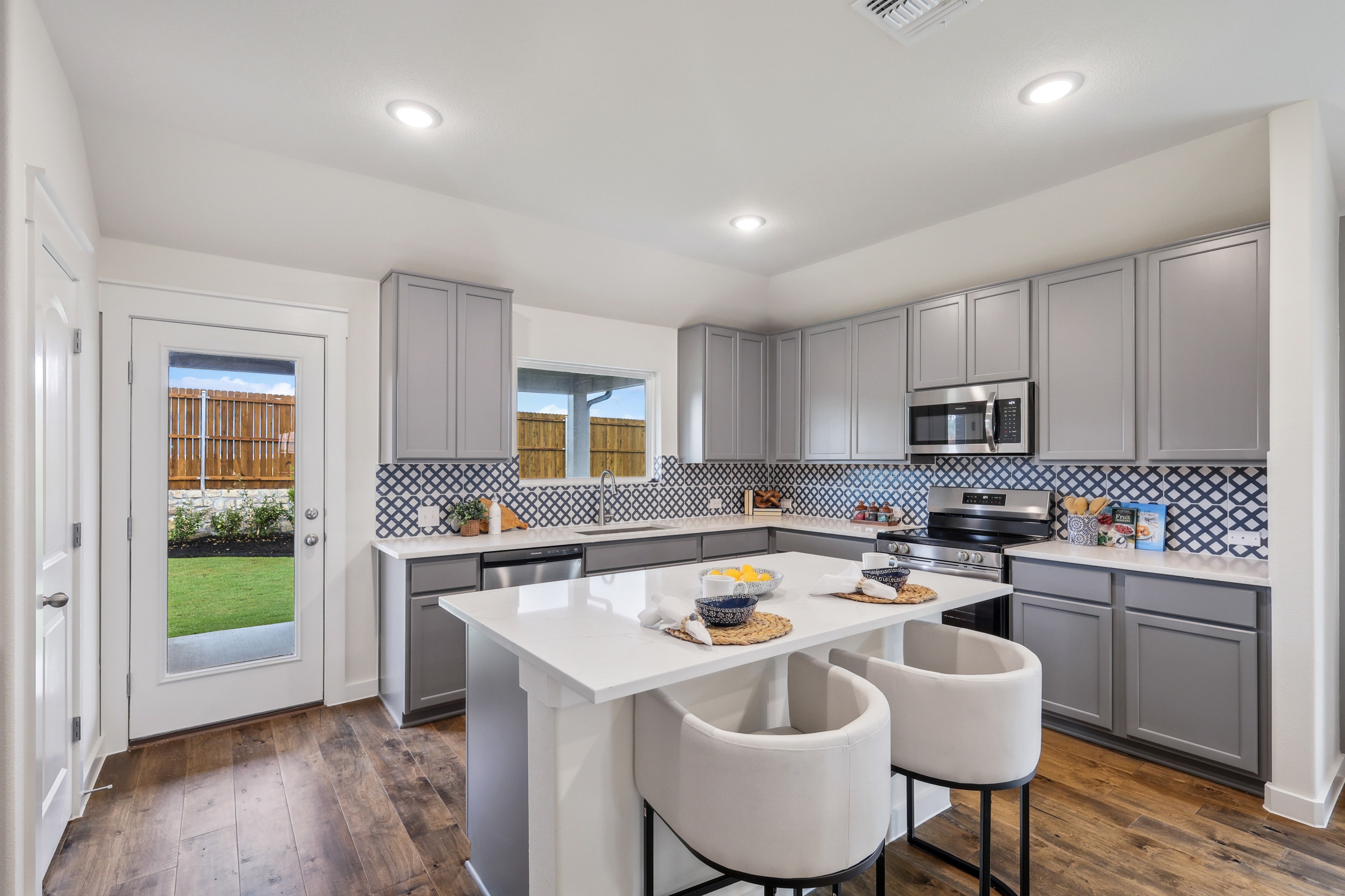 Stylish modern kitchen with gray cabinets, patterned backsplash, and kitchen island in Churchill community.