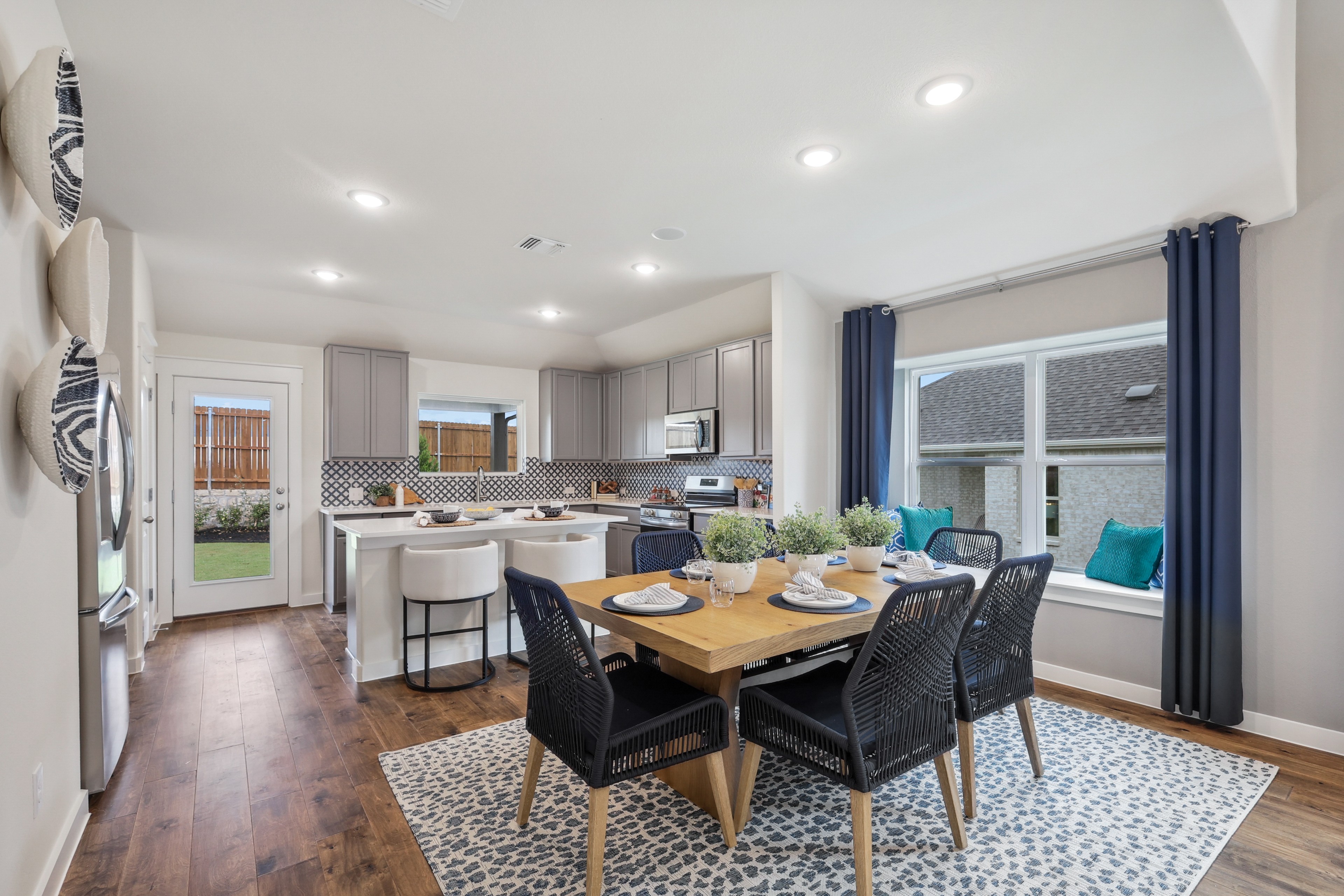 Spacious kitchen-dining area with hardwood floors, modern cabinets, and large windows in Churchill community home.