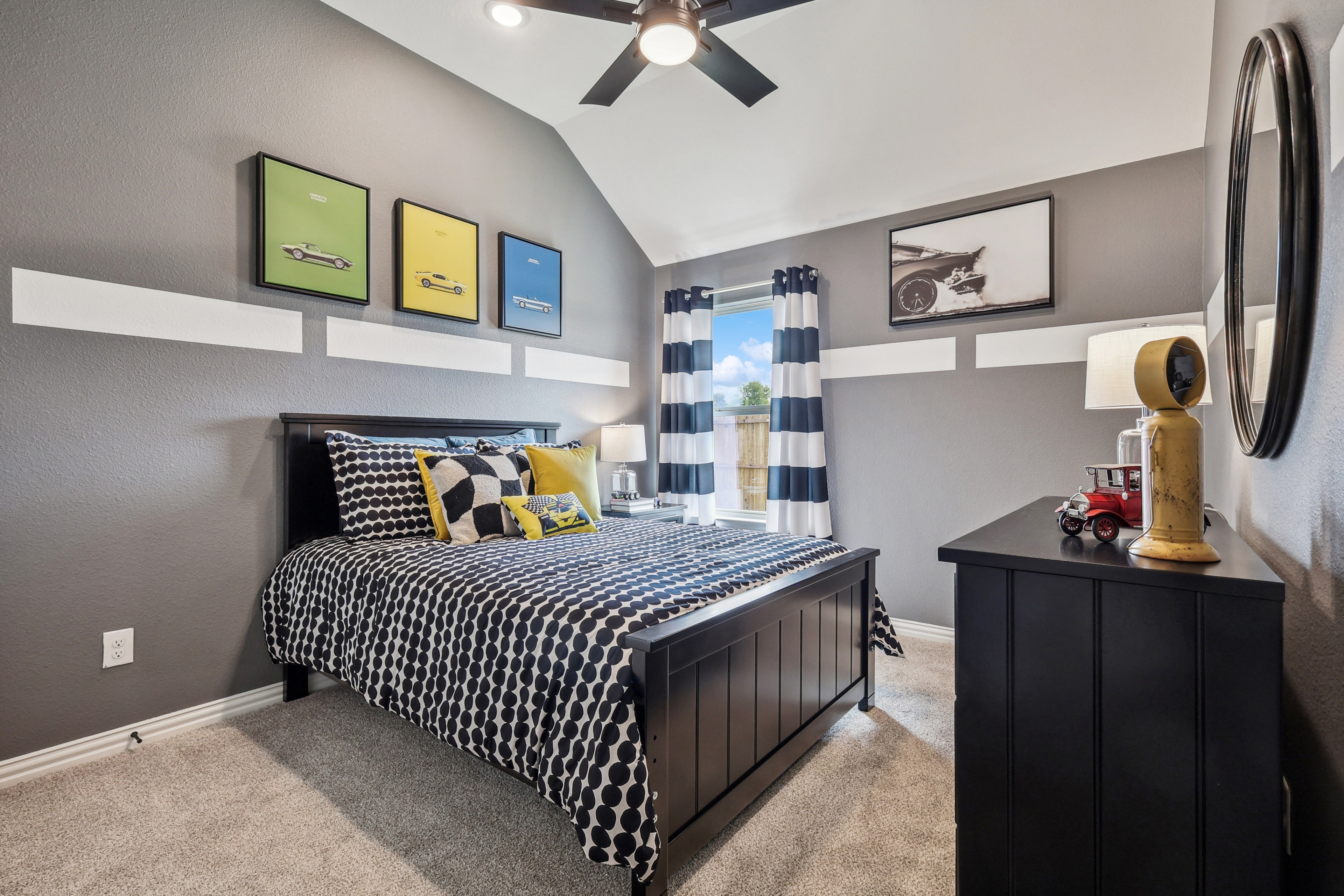 Modern bedroom with vaulted ceiling, vibrant car art, and striped curtains in Churchill community.