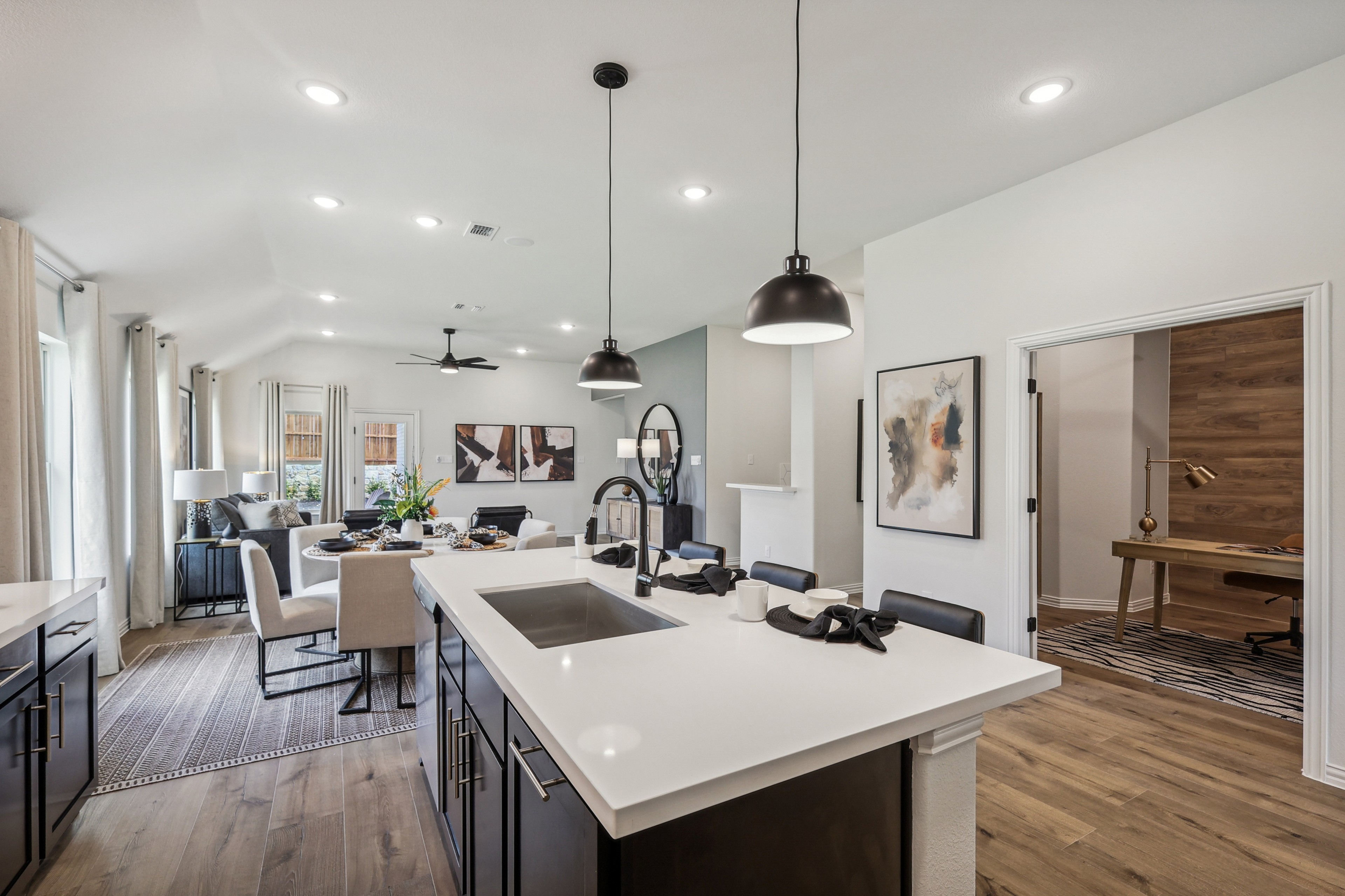 Modern open-plan kitchen and living area with sleek island, pendant lights, and wood flooring in Churchill community.