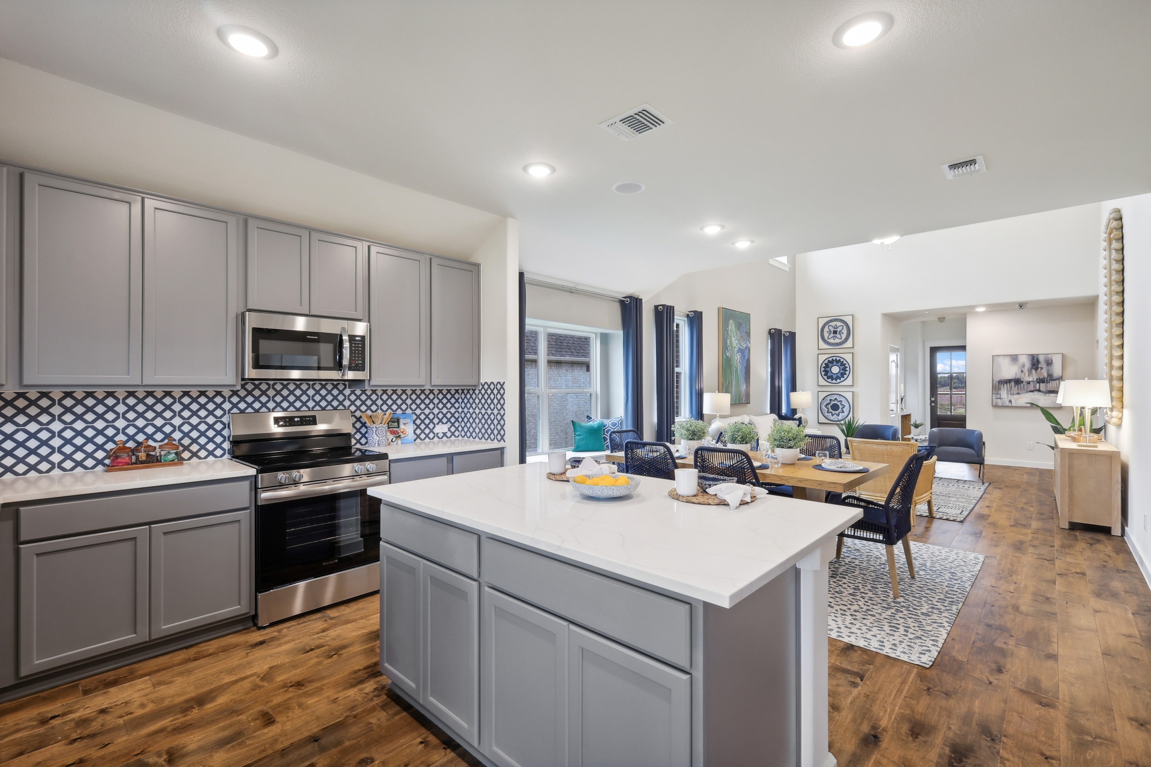 Modern kitchen and dining room with gray cabinets and patterned backsplash in Churchill community home.