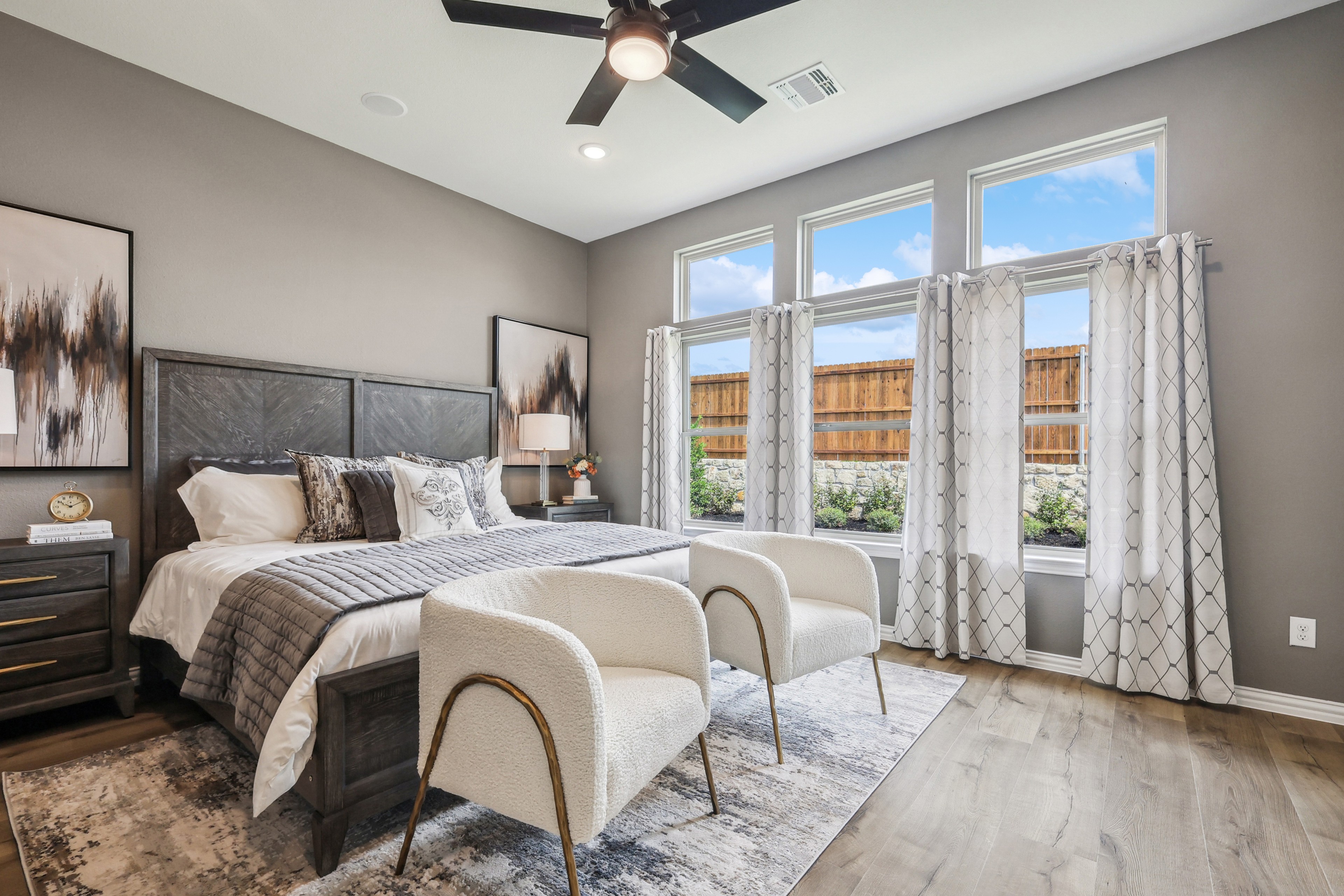 Modern bedroom with large windows, elegant decor, and plush seating in Churchill community home.