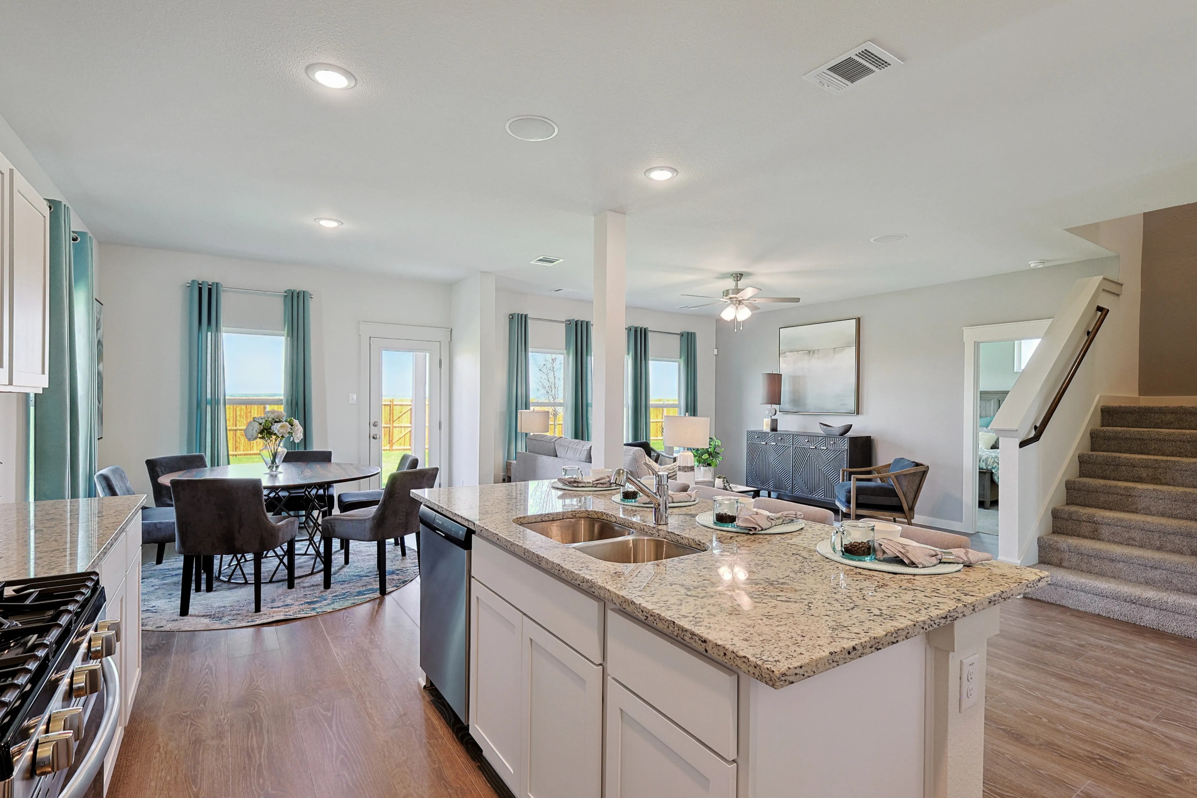 Open-concept kitchen and dining in luxury Patriot Estates home, featuring granite countertops and hardwood floors.