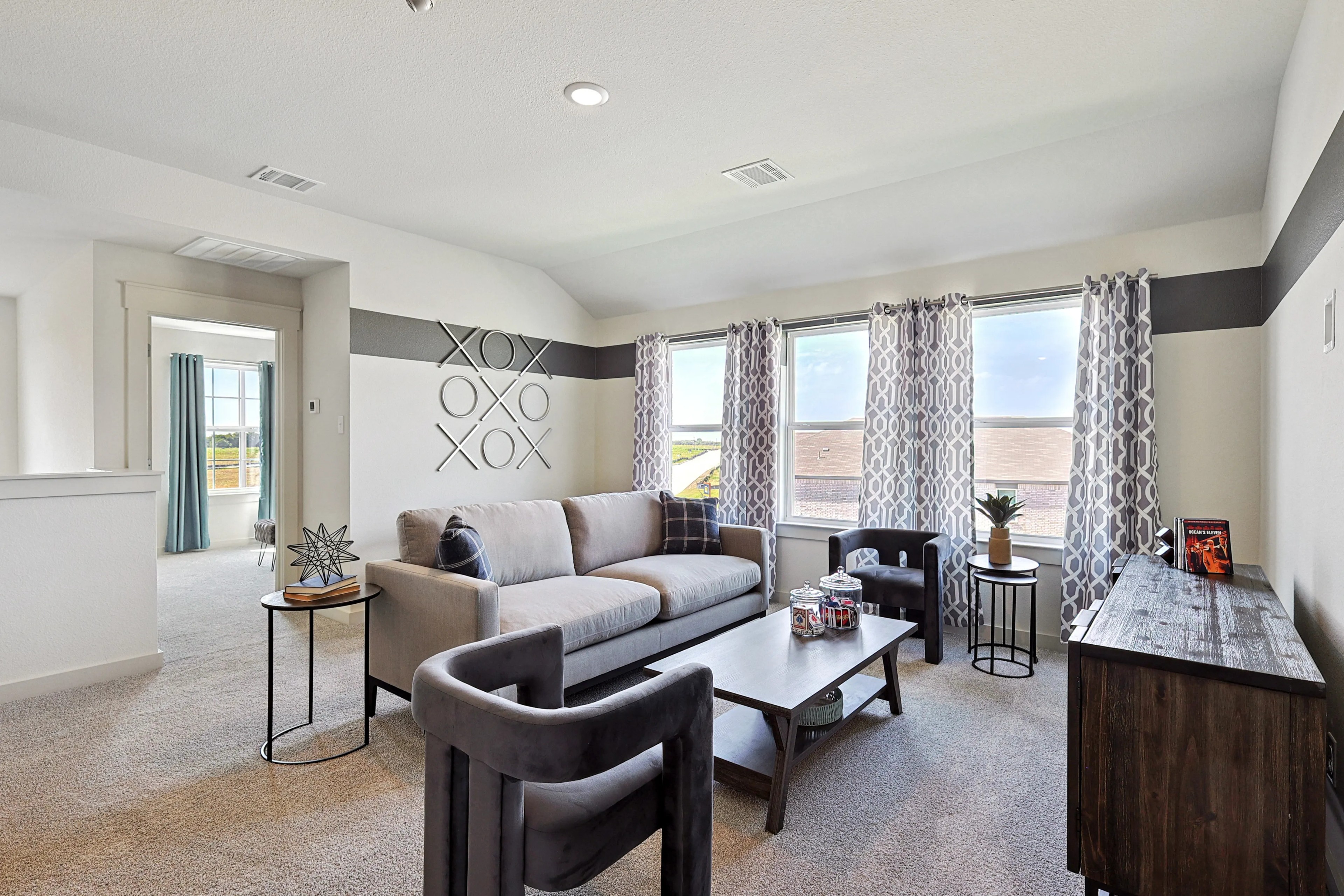 Modern living room with gray sofa, abstract wall art, large windows, and stylish decor in Patriot Estates.