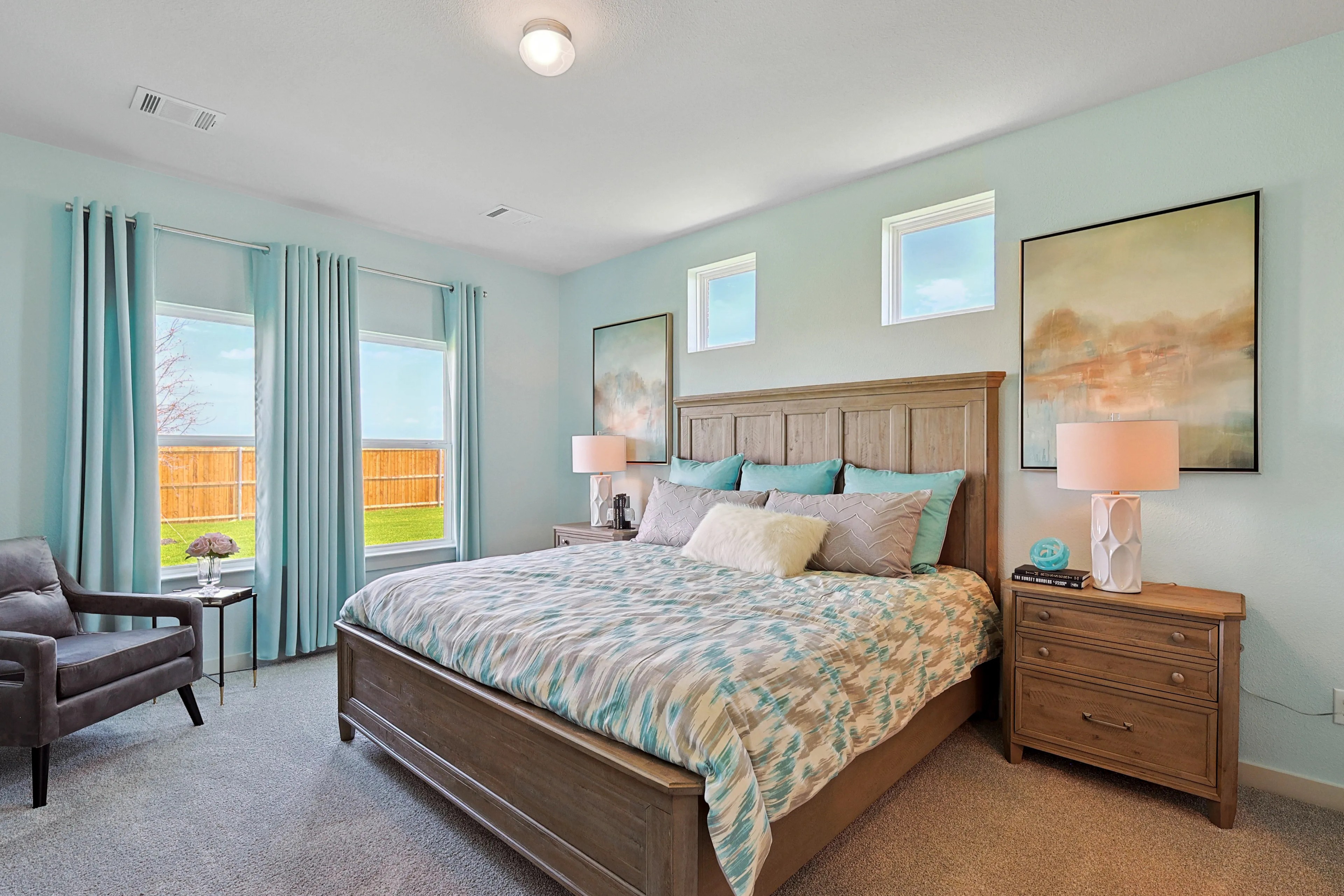 Elegant bedroom with wooden bedframe and large windows, Patriot Estates community.