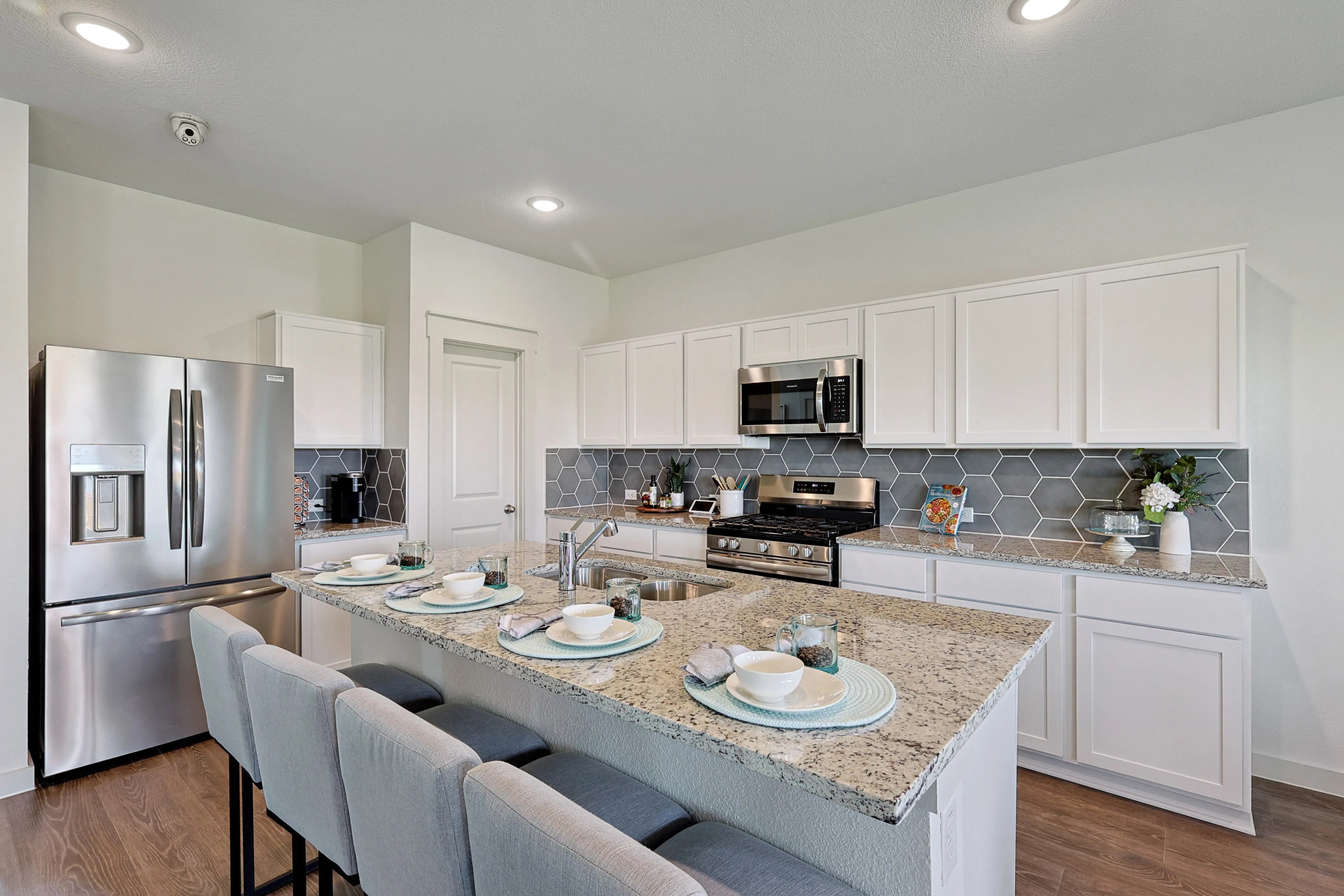 Modern kitchen with granite countertops, hexagonal backsplash, stainless appliances in Patriot Estates.