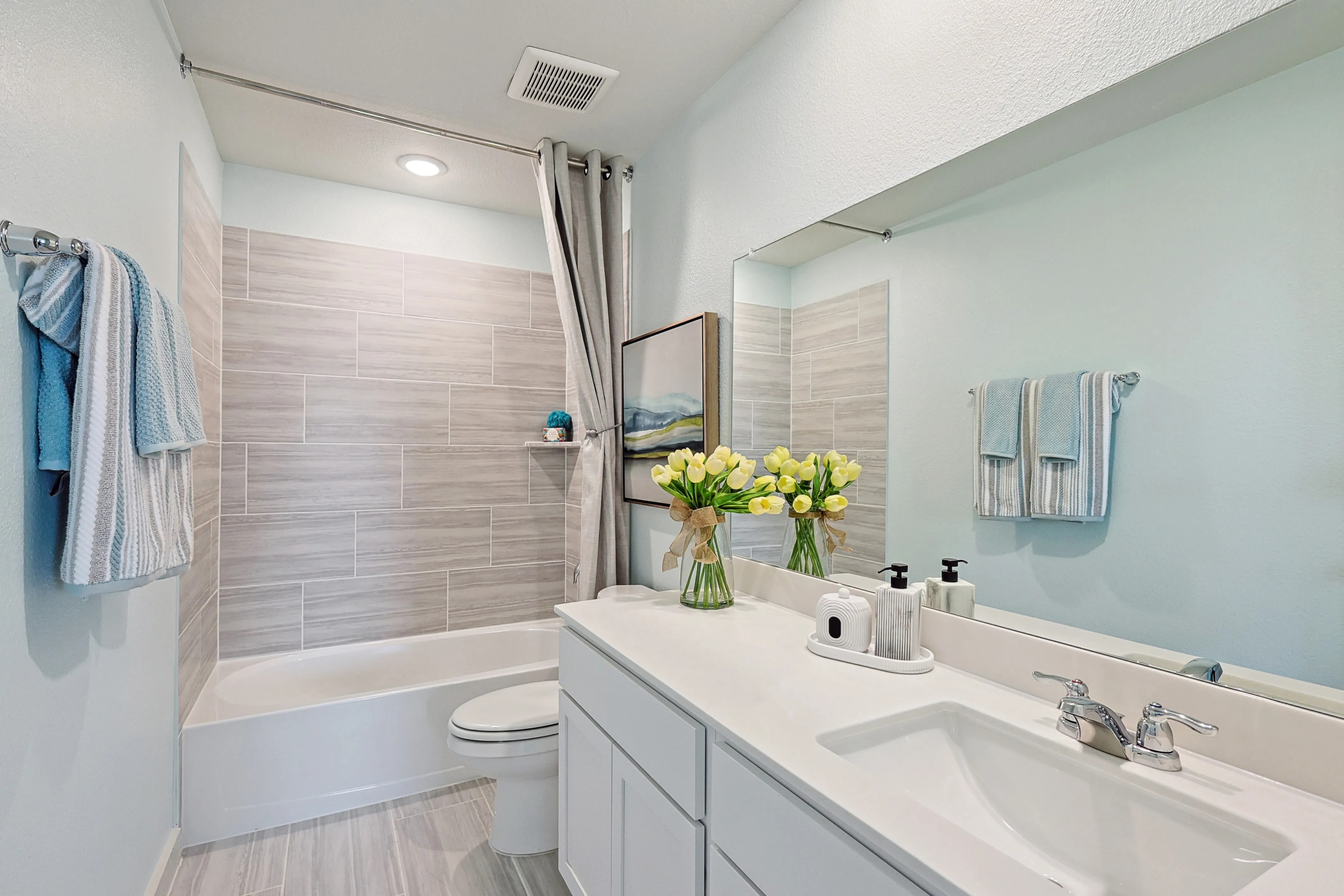 Elegant bathroom with light gray tiles, modern fixtures, and fresh tulips, Patriot Estates.