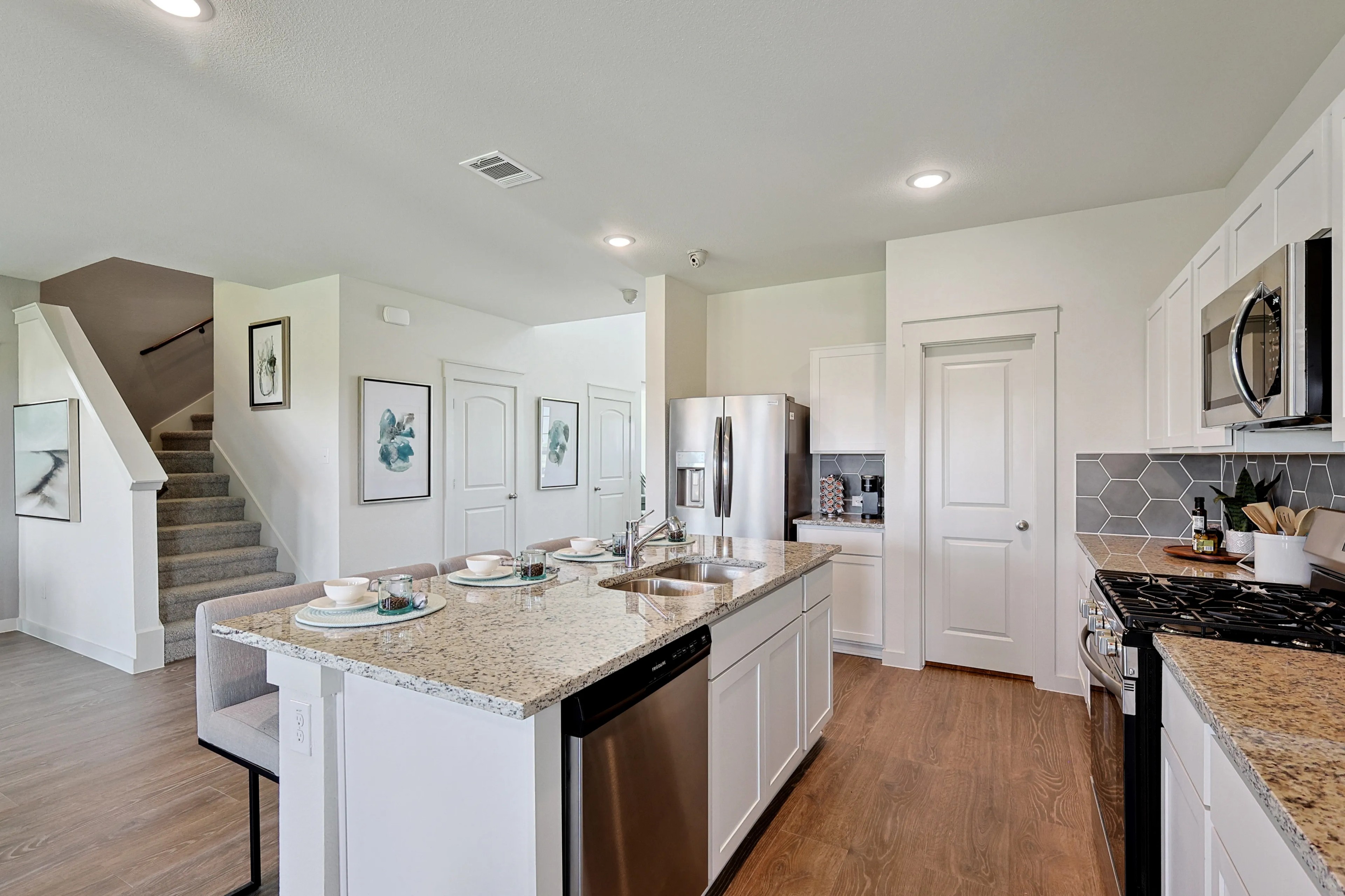Modern kitchen with granite countertops and island in Patriot Estates. Hexagonal tile backsplash, stainless appliances.