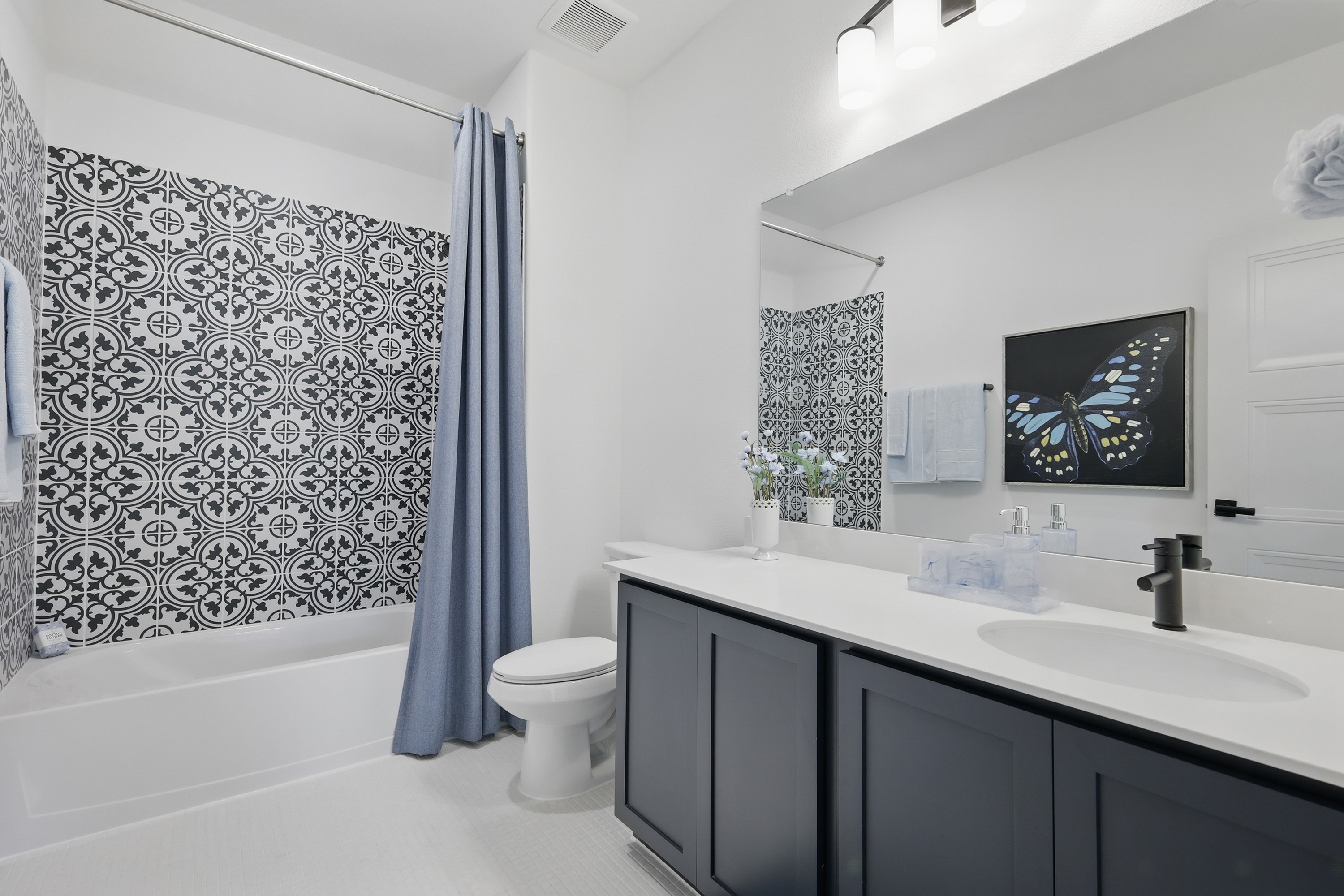 Modern bathroom with patterned tile, black vanity, and blue accents in Westridge community.