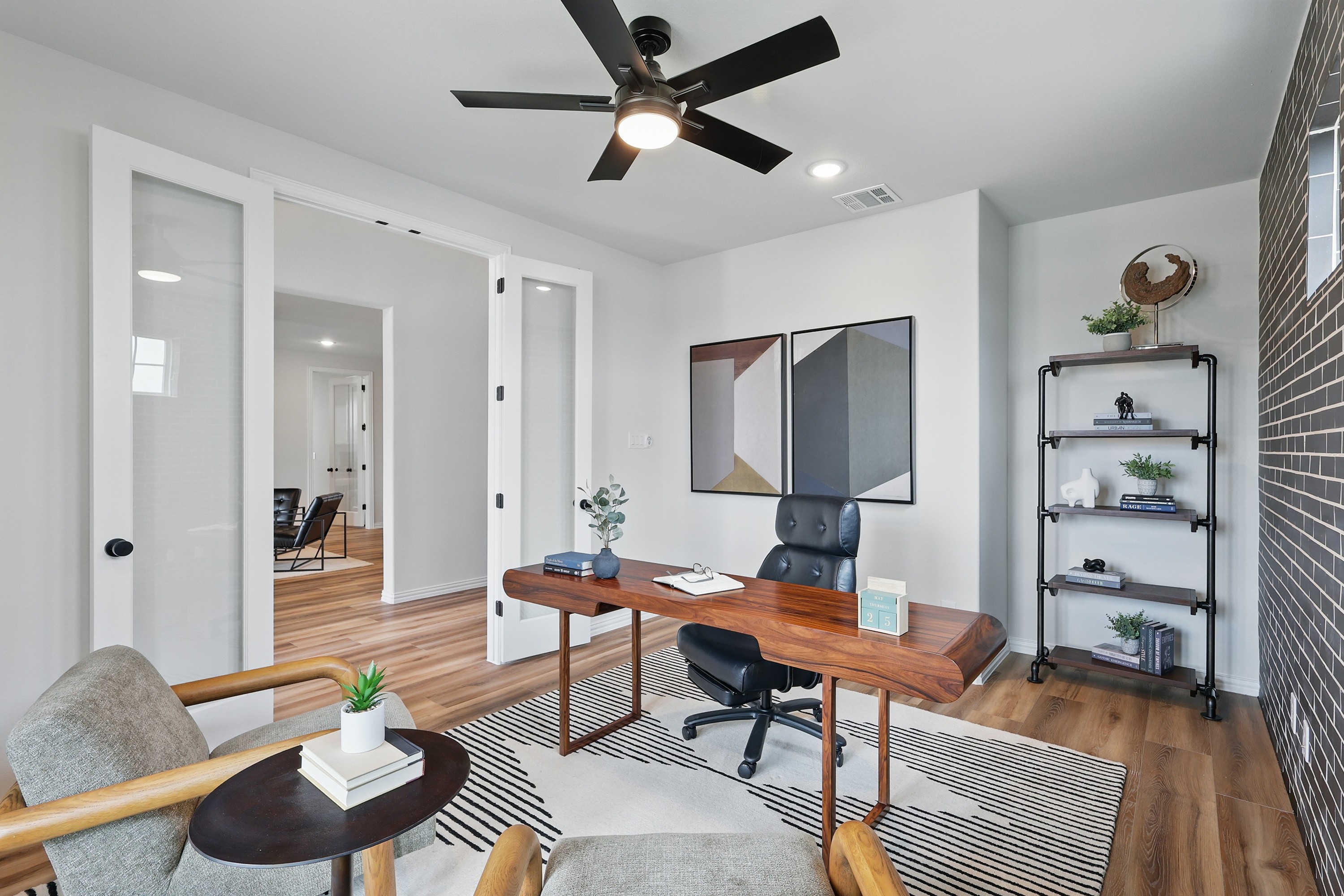 Modern home office with wood desk, art, glass doors, and black fan in Westridge community.