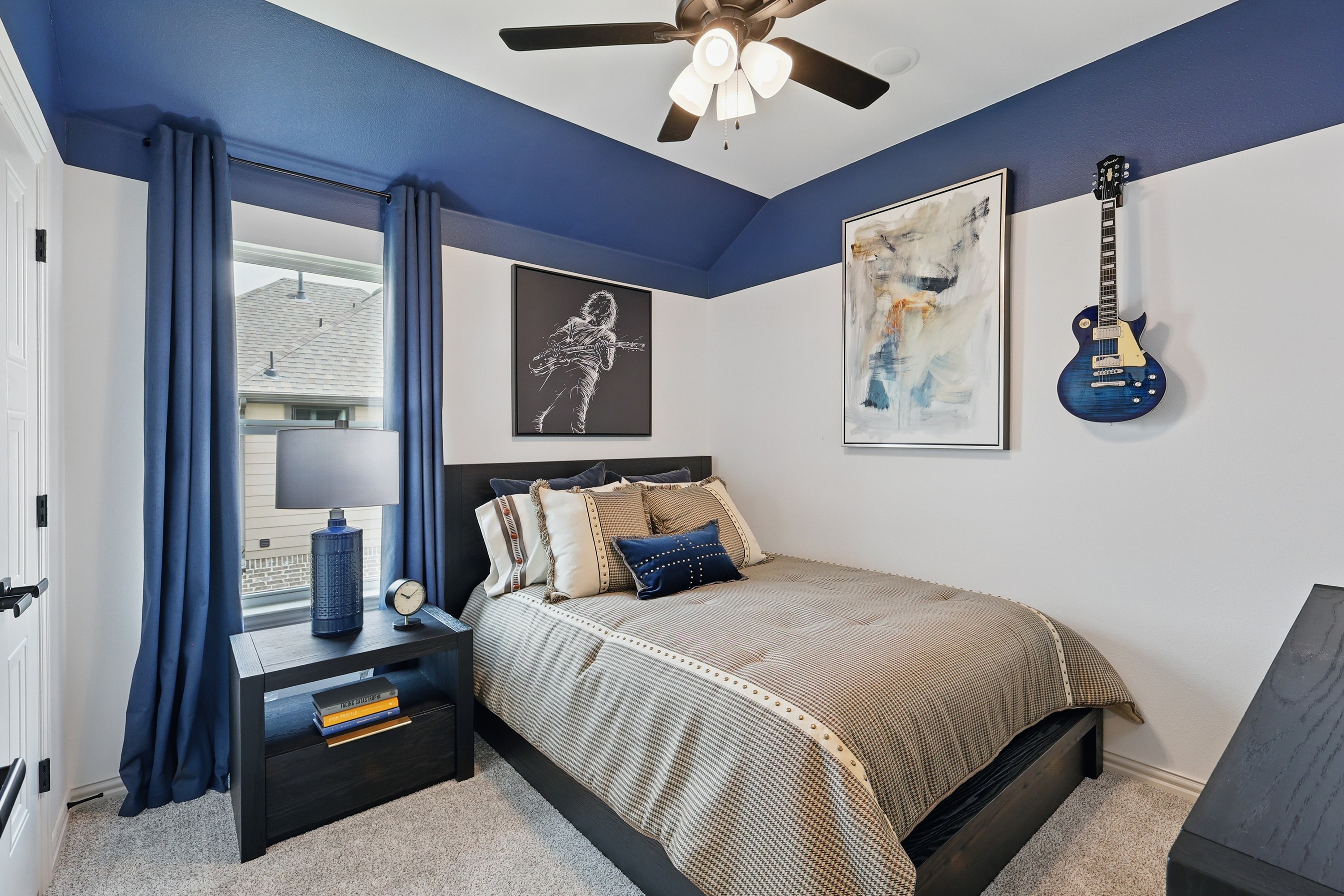 Cozy bedroom with blue accents, stylish wall art, and decorative guitar in Westridge community.