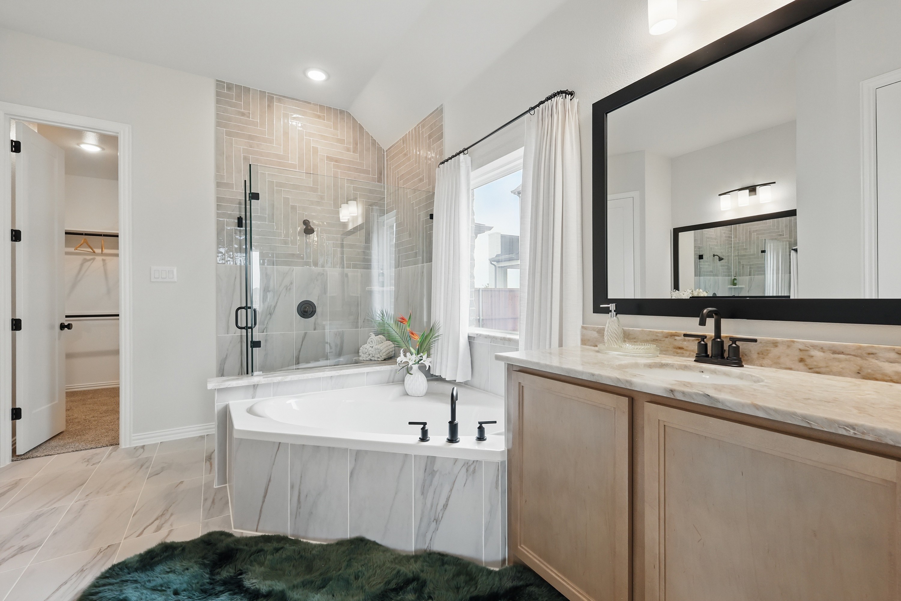 Luxurious bathroom with marble tub, glass shower, tiled walls, and large mirror in Westridge community.