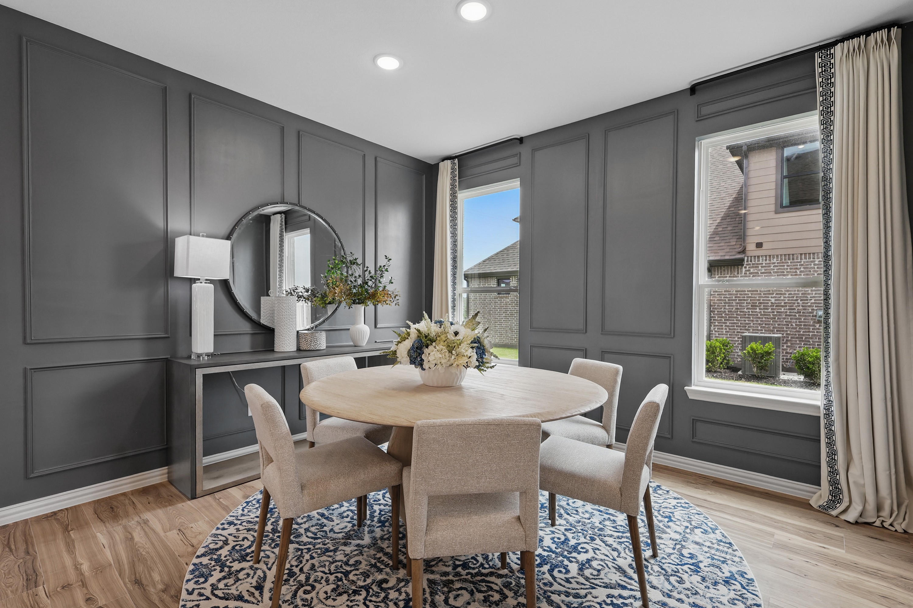 Chic dining area with round table, gray paneled walls, and large windows in Westridge community.