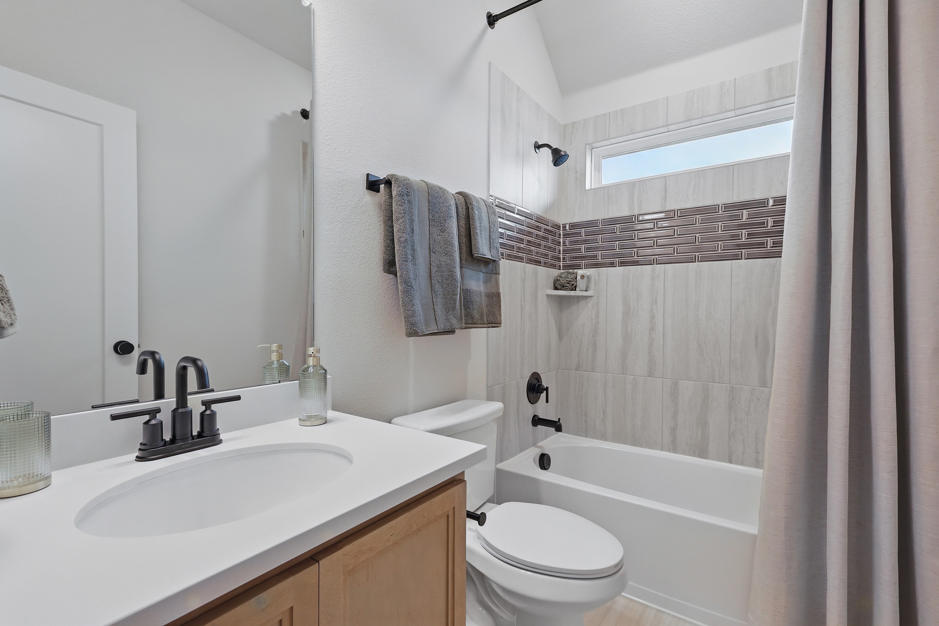 Elegant bathroom with modern fixtures, marble tiles, and accent wall in Westridge community.