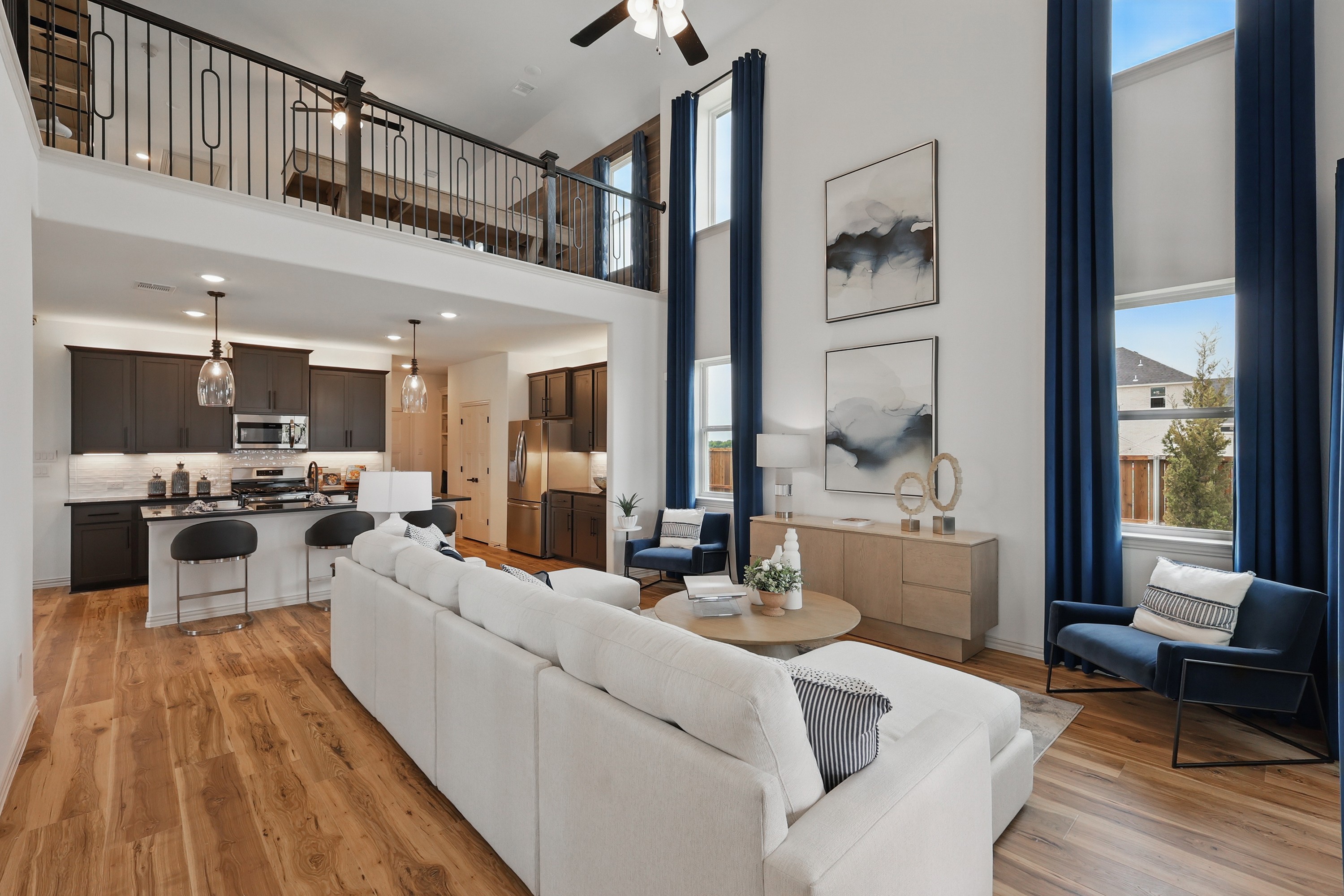 Modern open-concept living area with high ceiling, wood floors, and balcony in Westridge community home.