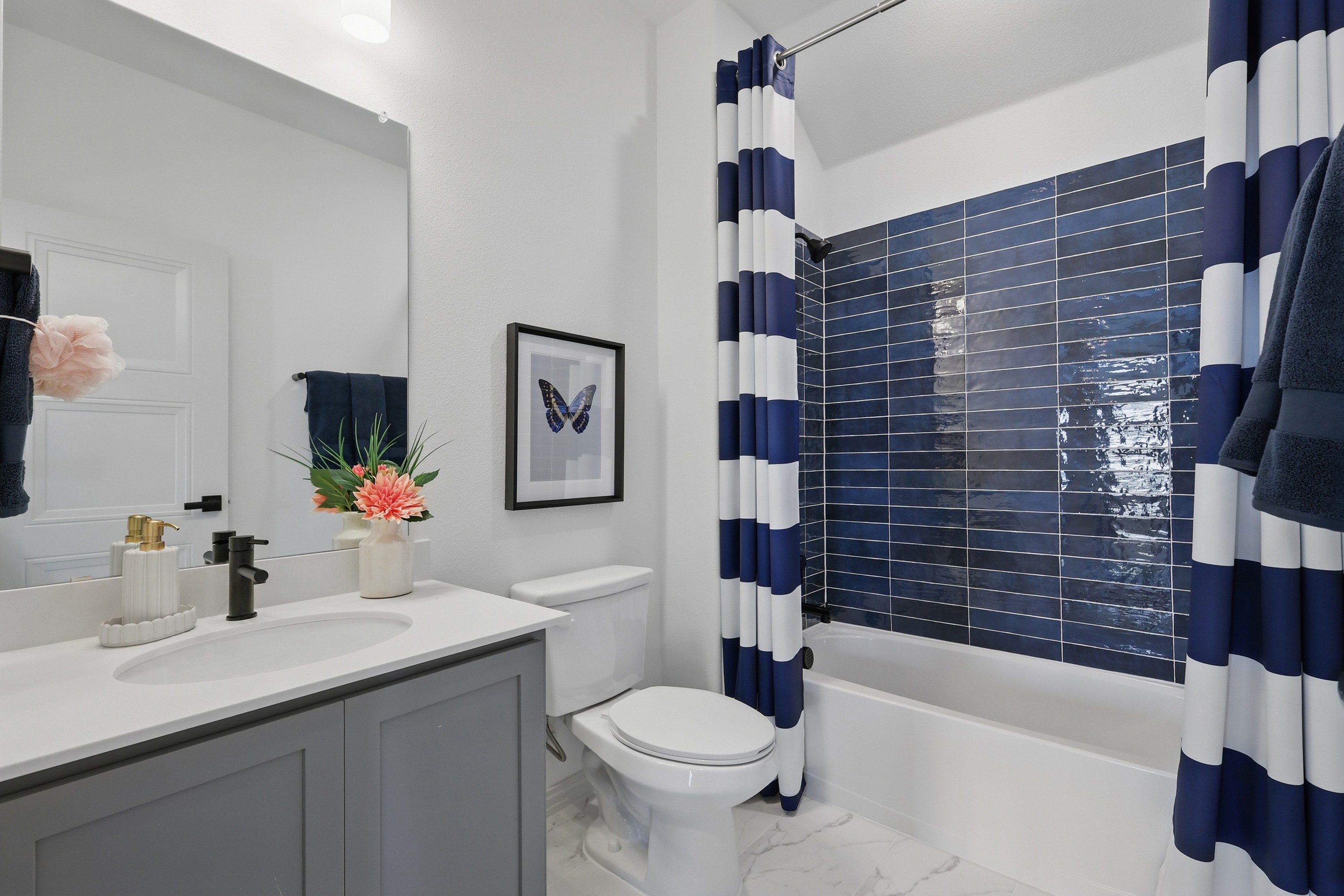 Modern bathroom with navy tiles, striped shower curtain, elegant vanity, Westridge community.