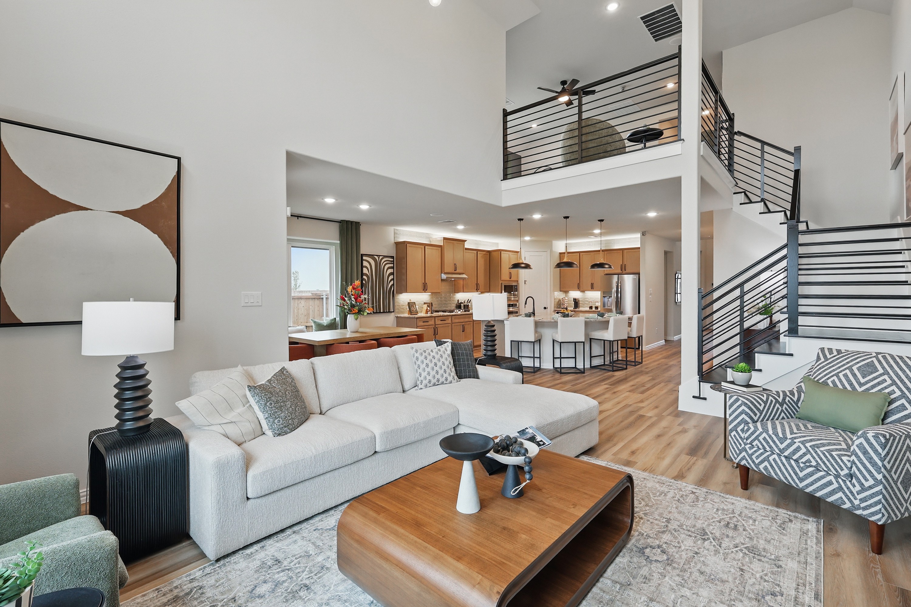 Modern living room in Westridge with open layout, gray couch, stylish decor, wood floors, loft, sleek staircase.