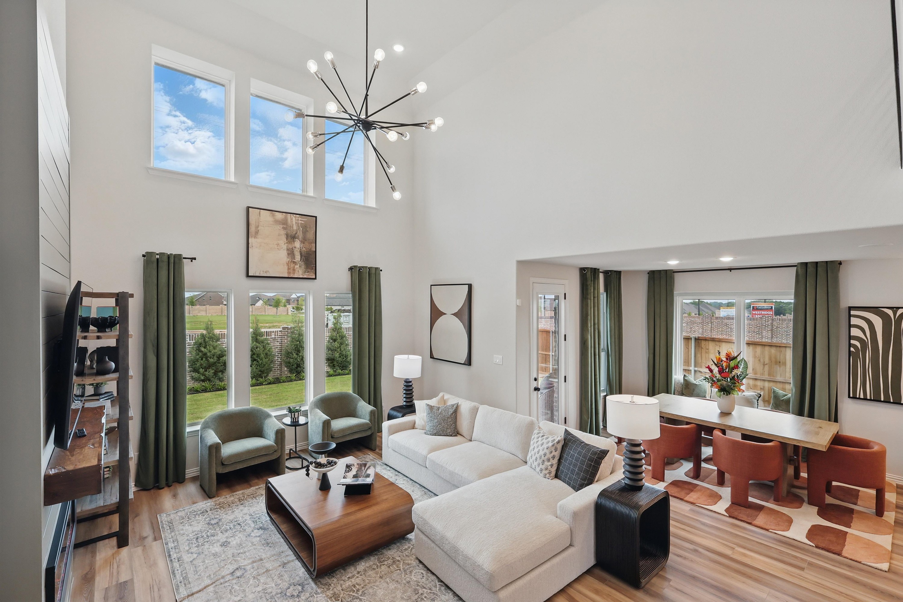 Spacious living room with high ceilings, modern chandelier, large windows, and garden view in Westridge community.