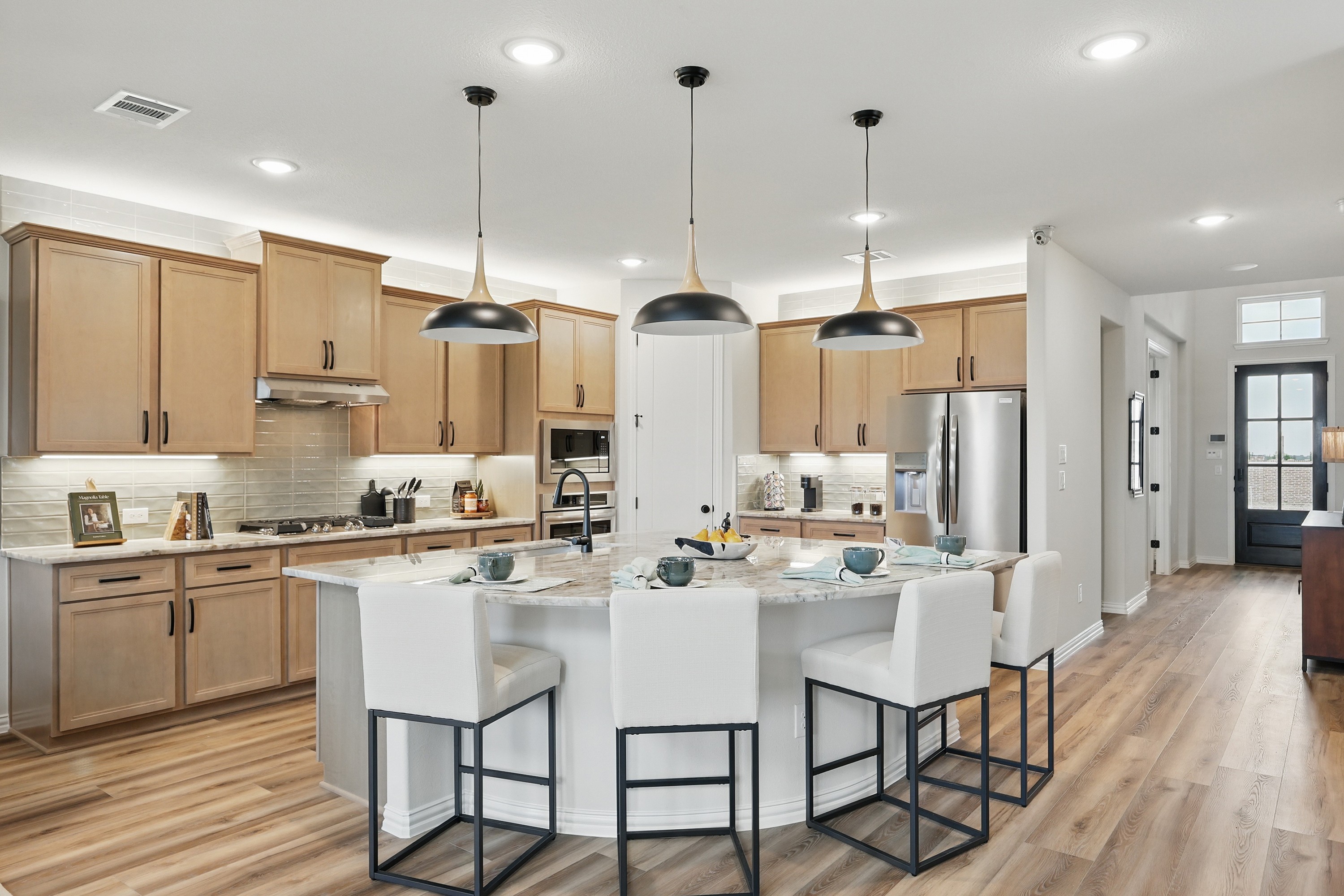 Modern kitchen with lightwood cabinets, marble island, pendant lights in Westridge community.
