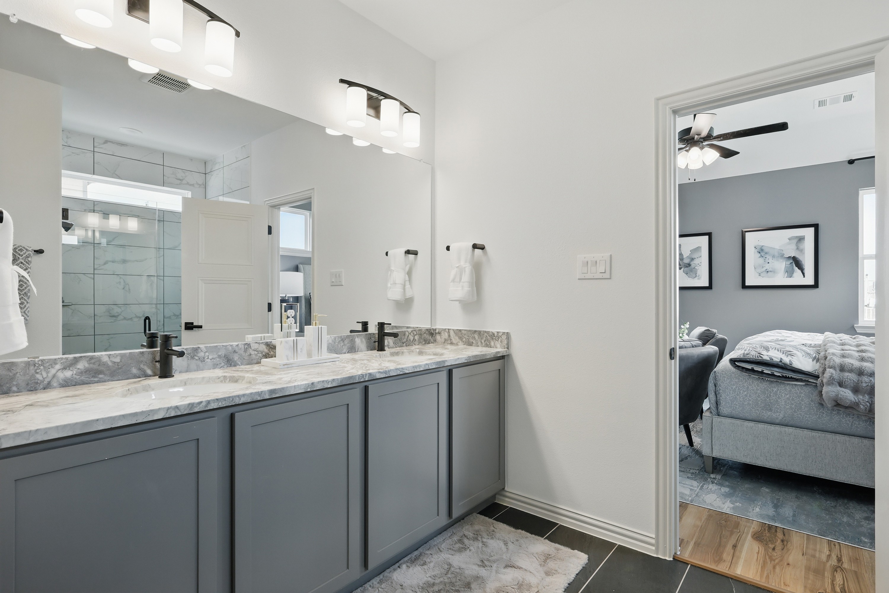 Modern Westridge bathroom with marble double vanity, sleek black fixtures, and spacious shower. Bedroom visible through door.