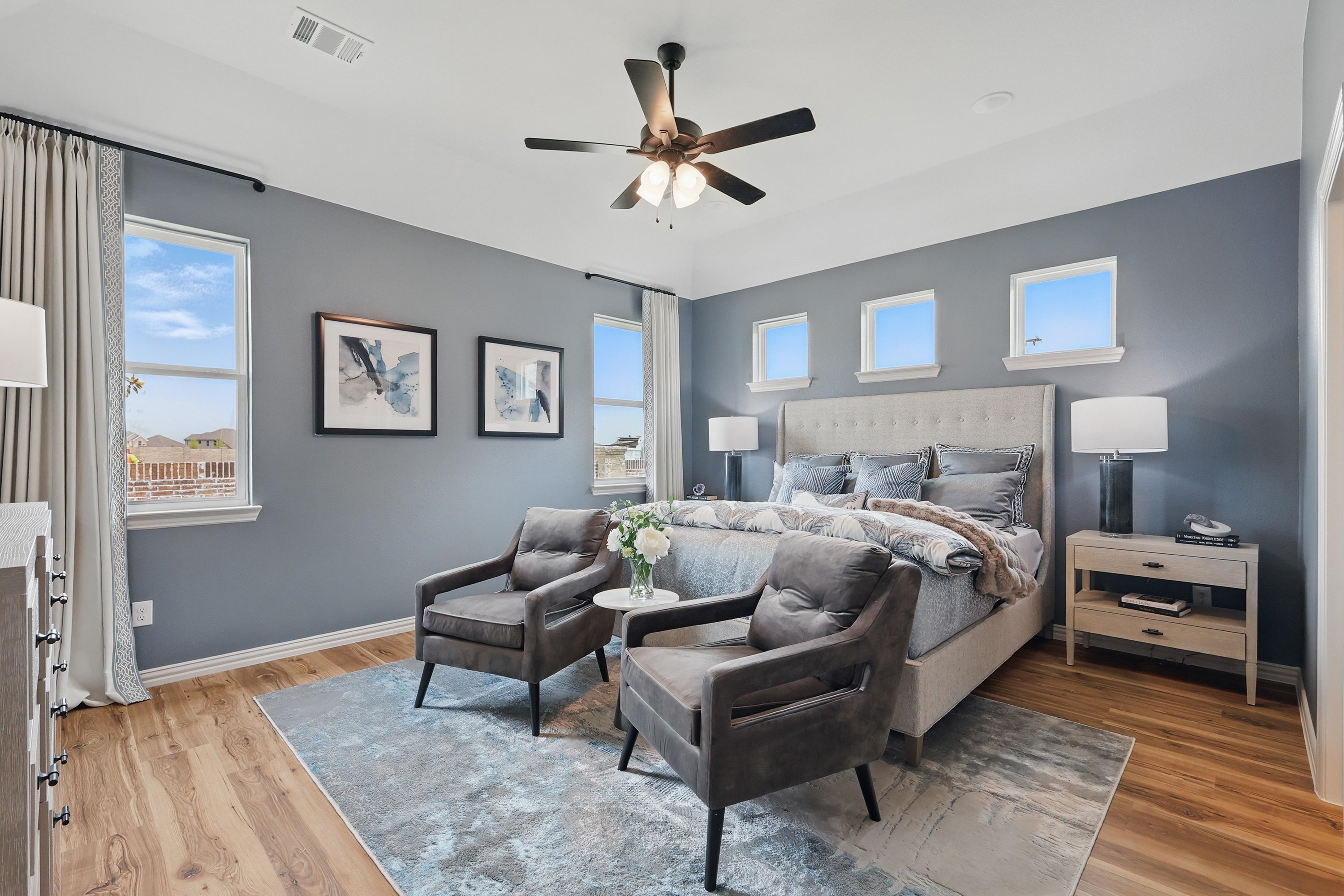 Elegant bedroom with gray walls, large windows, modern decor, and wood flooring in Westridge community.