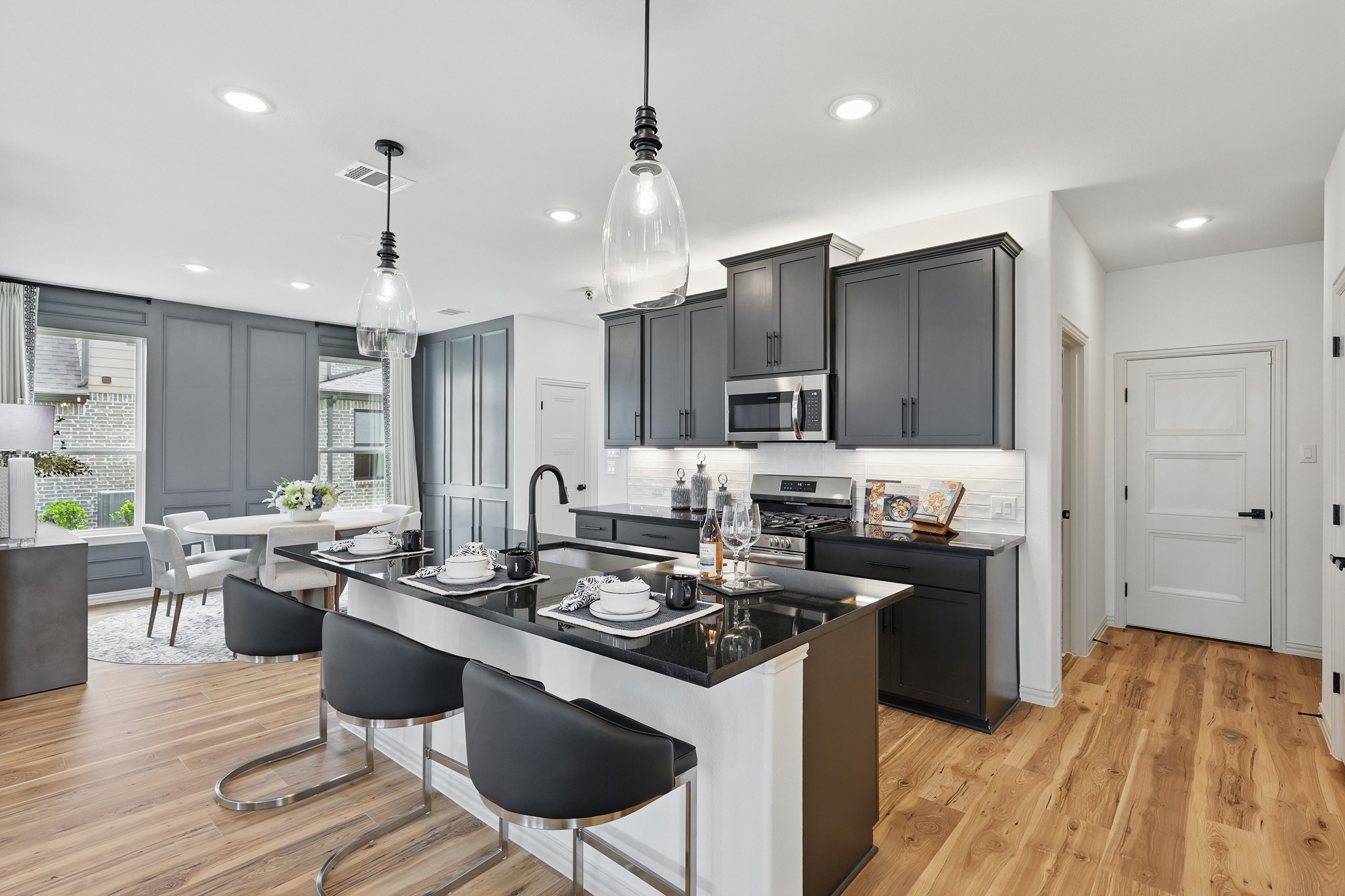 Modern kitchen with black cabinets, island seating, and wood floors in Westridge community home.