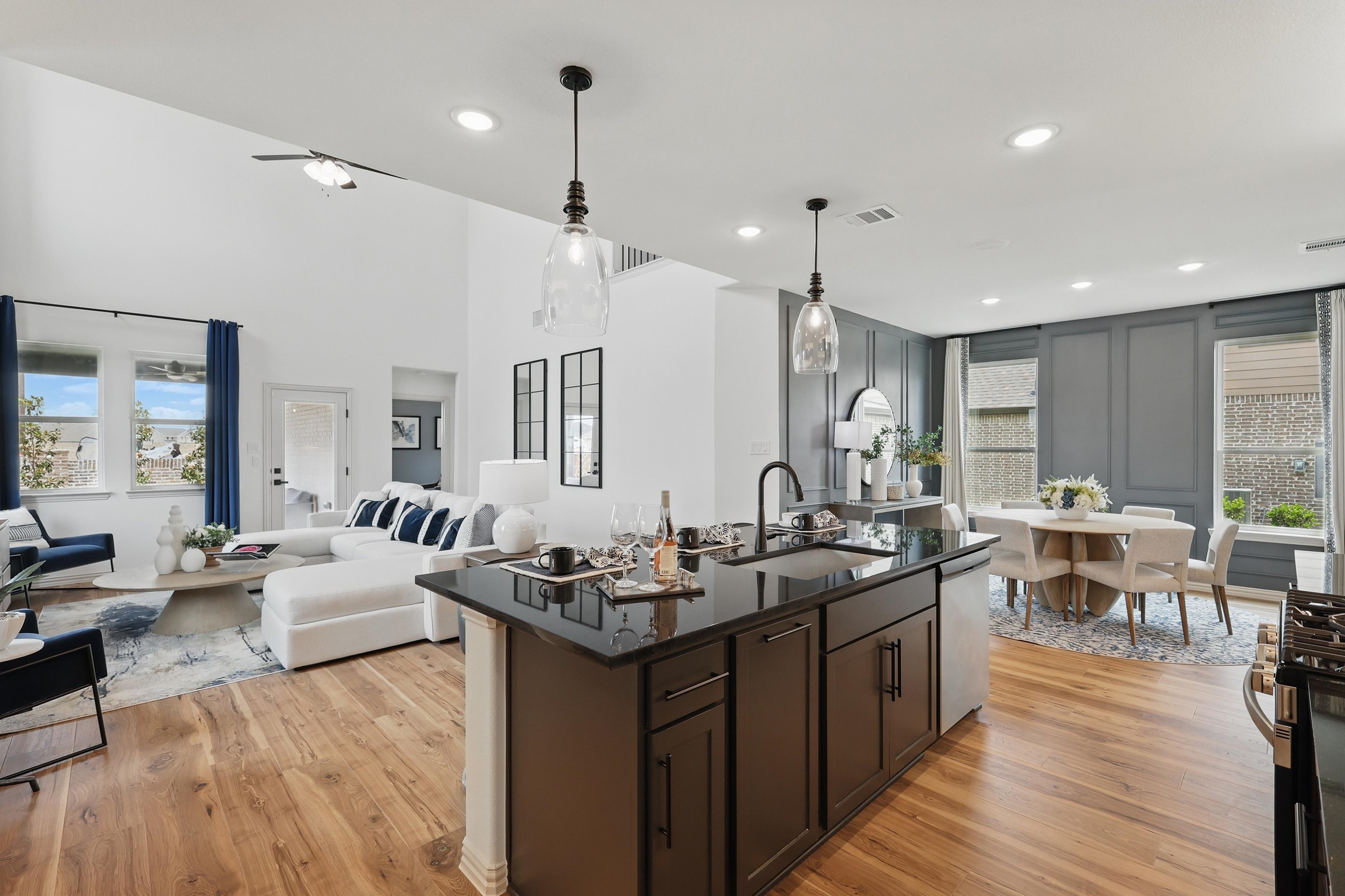Modern open-concept living room and kitchen with high ceilings, wood floors, and elegant furnishings in Westridge community.