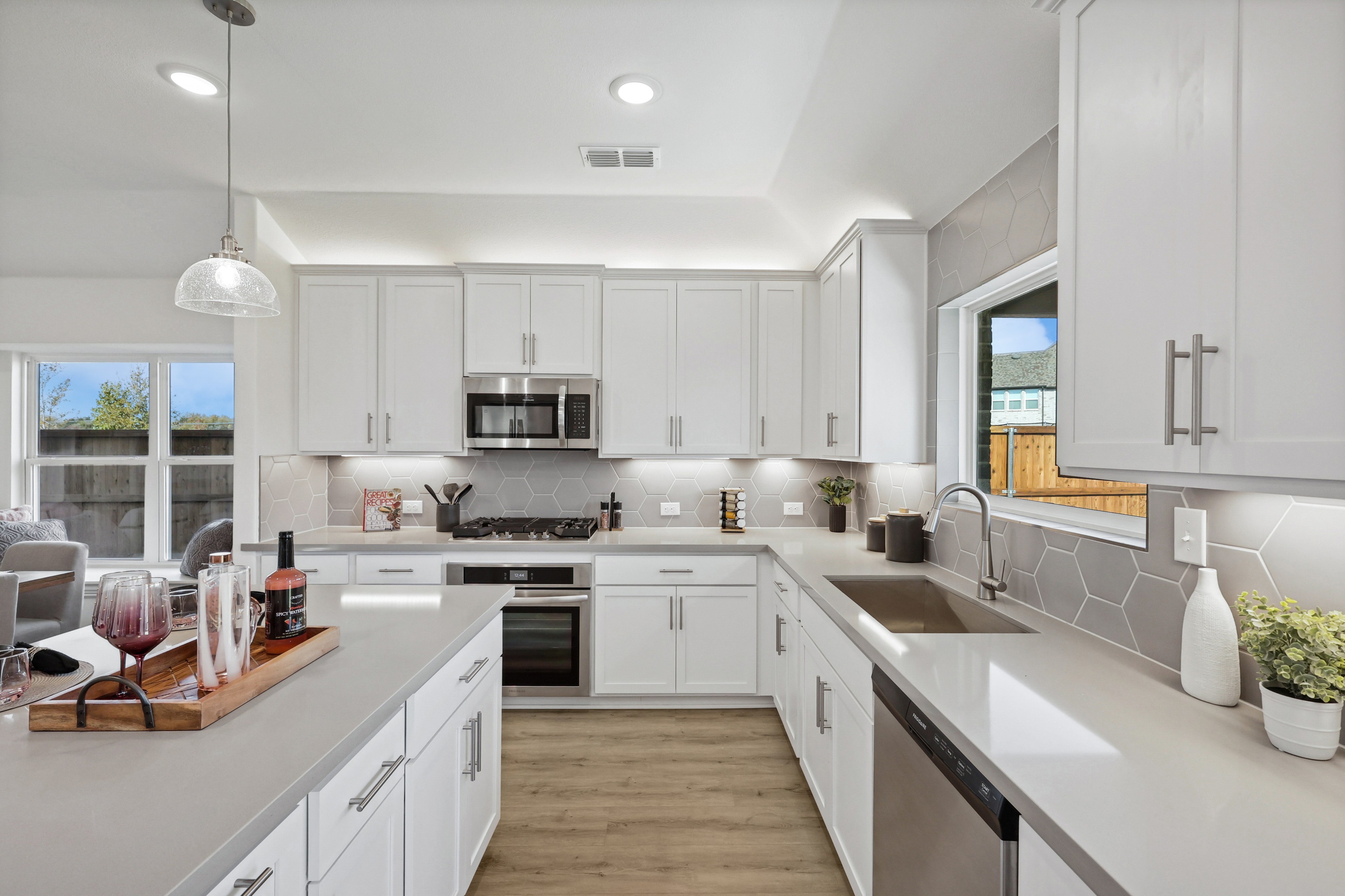 Modern kitchen with white cabinets, hexagonal backsplash, stainless appliances, located in Bel Air Village community.