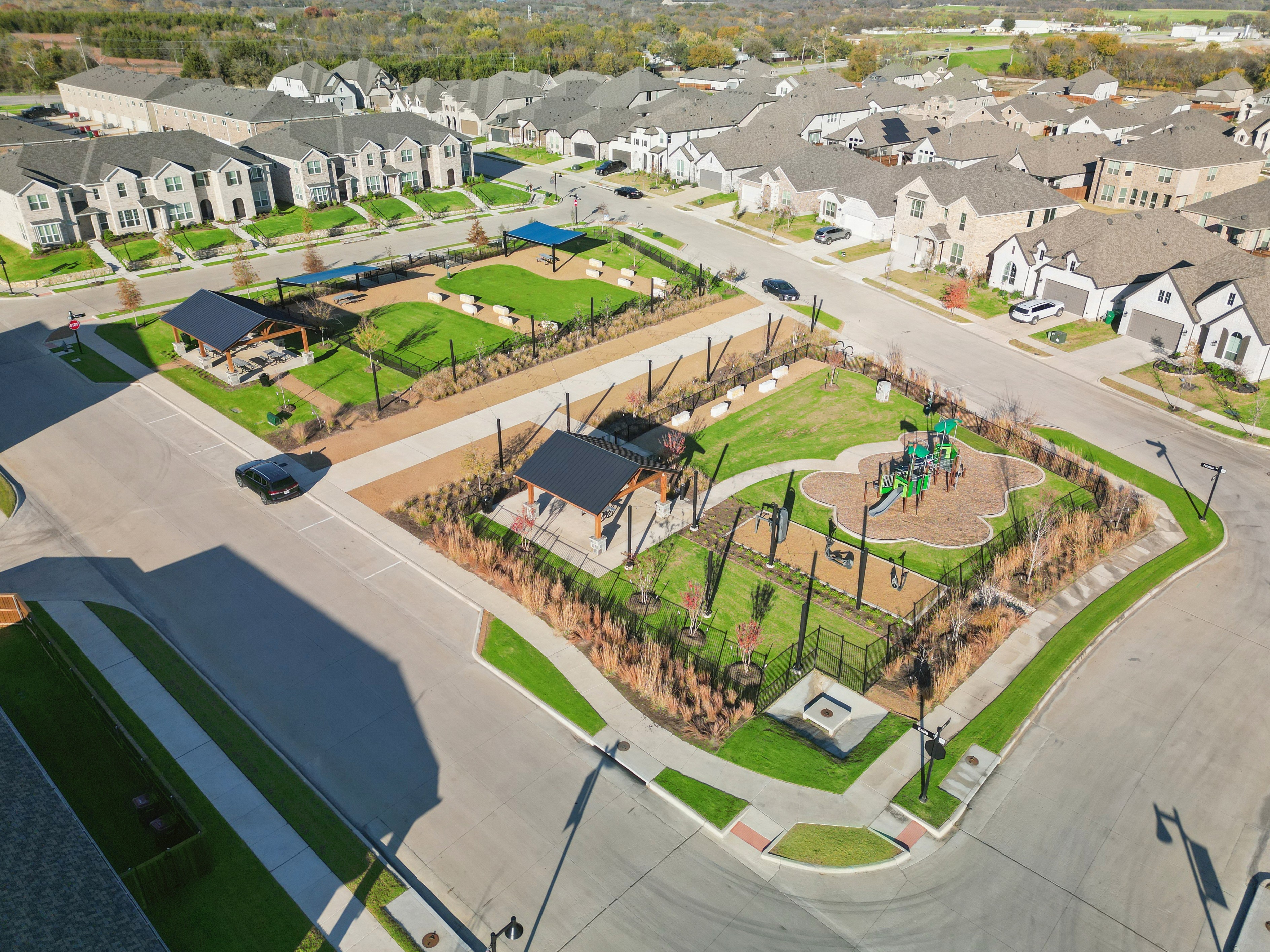Aerial view of Bel Air Village community with modern homes, lush parks, and a playground in a well-planned urban setting.