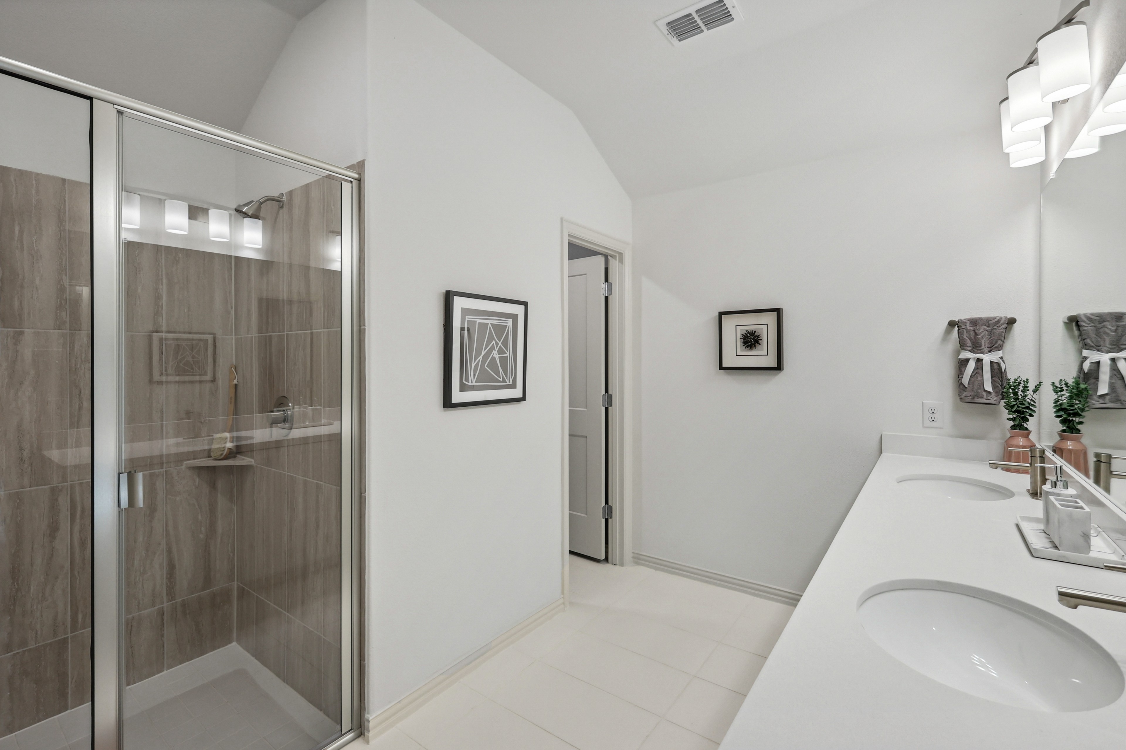 Modern bathroom with double sink vanity, frameless glass shower, in Bel Air Village. Minimalist decor, bright lighting.