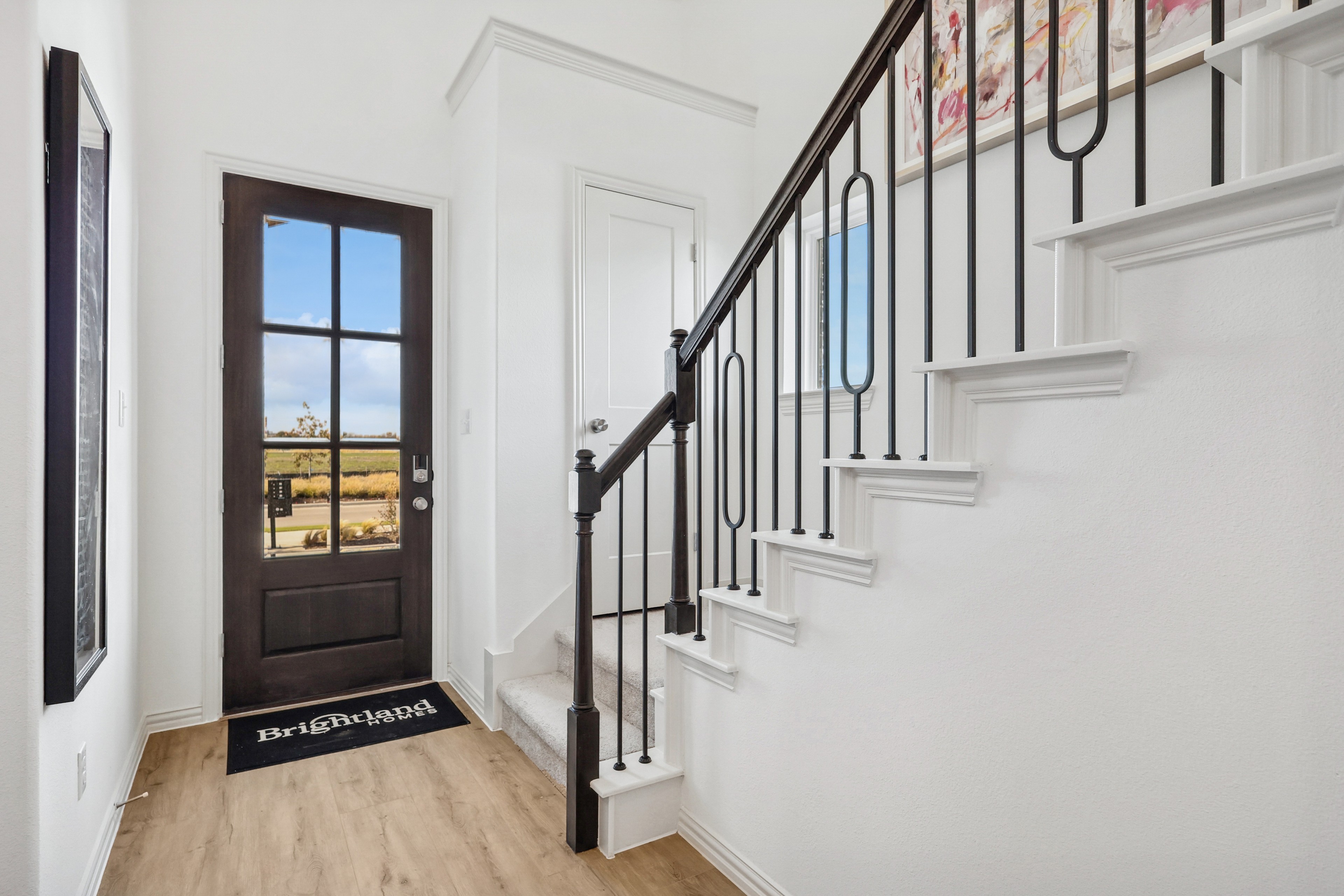 Elegant Bel Air Village foyer with wooden floor, black-framed glass door, and chic staircase.