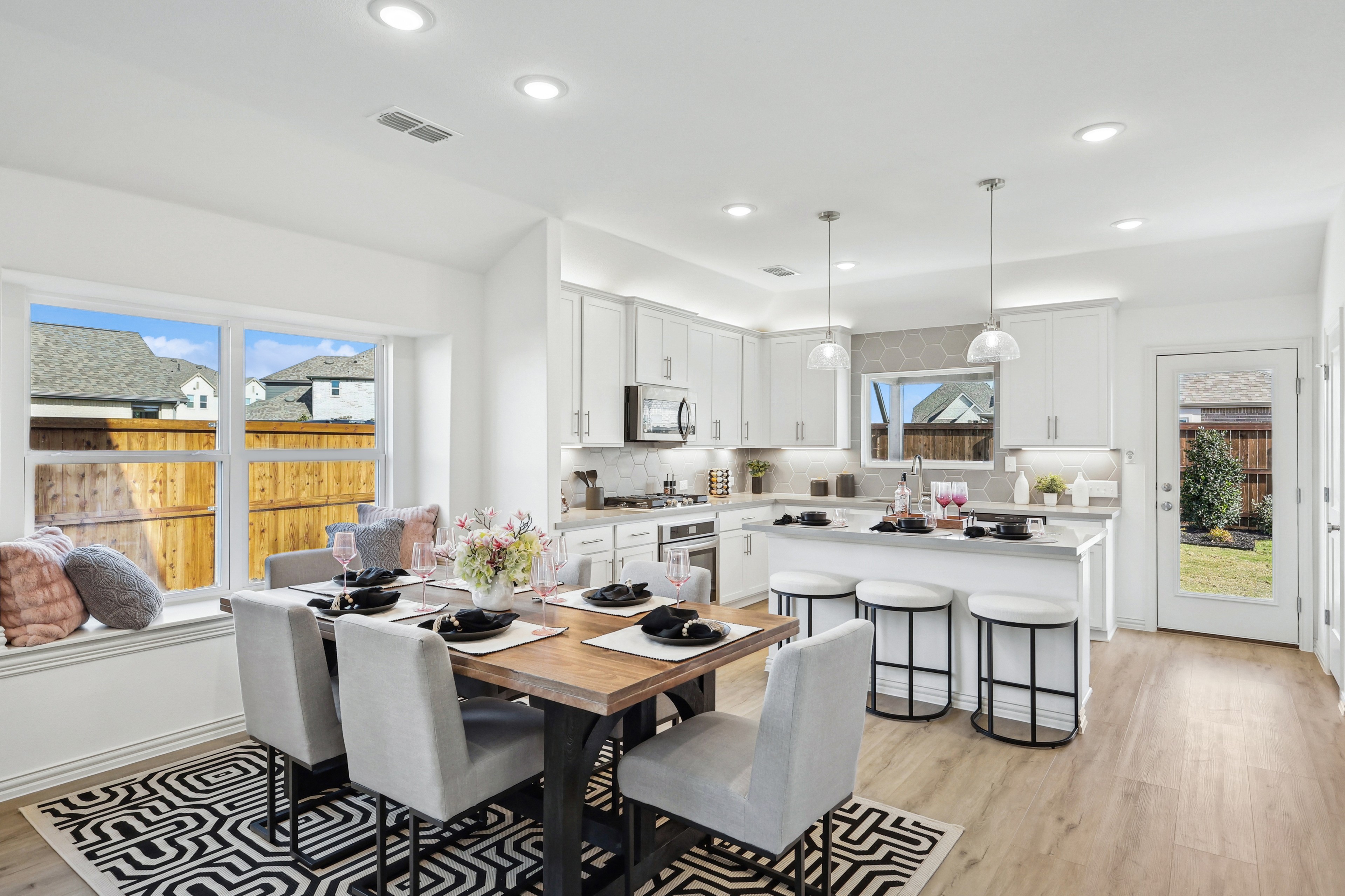 Modern Bel Air Village kitchen-dining area with island, pendant lights, window seat, garden view.