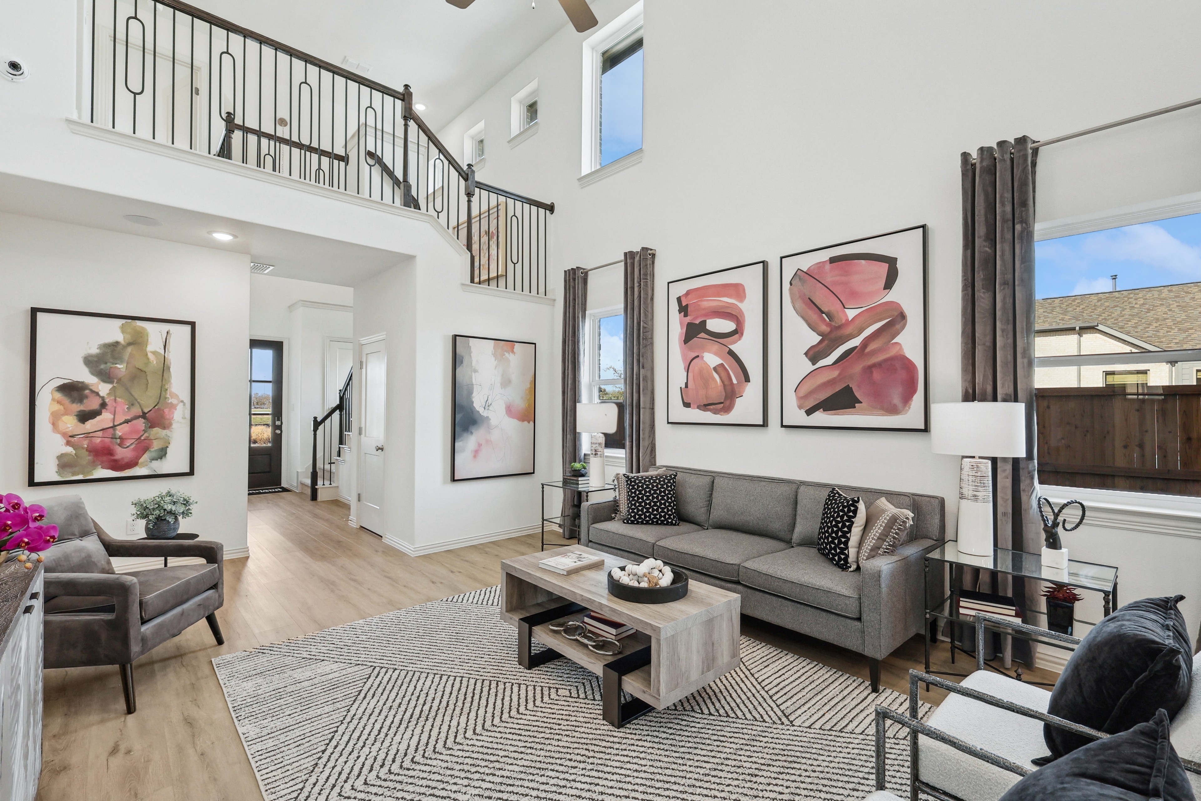 Spacious living room with modern art, high ceilings, elegant railing, and large windows in Bel Air Village.