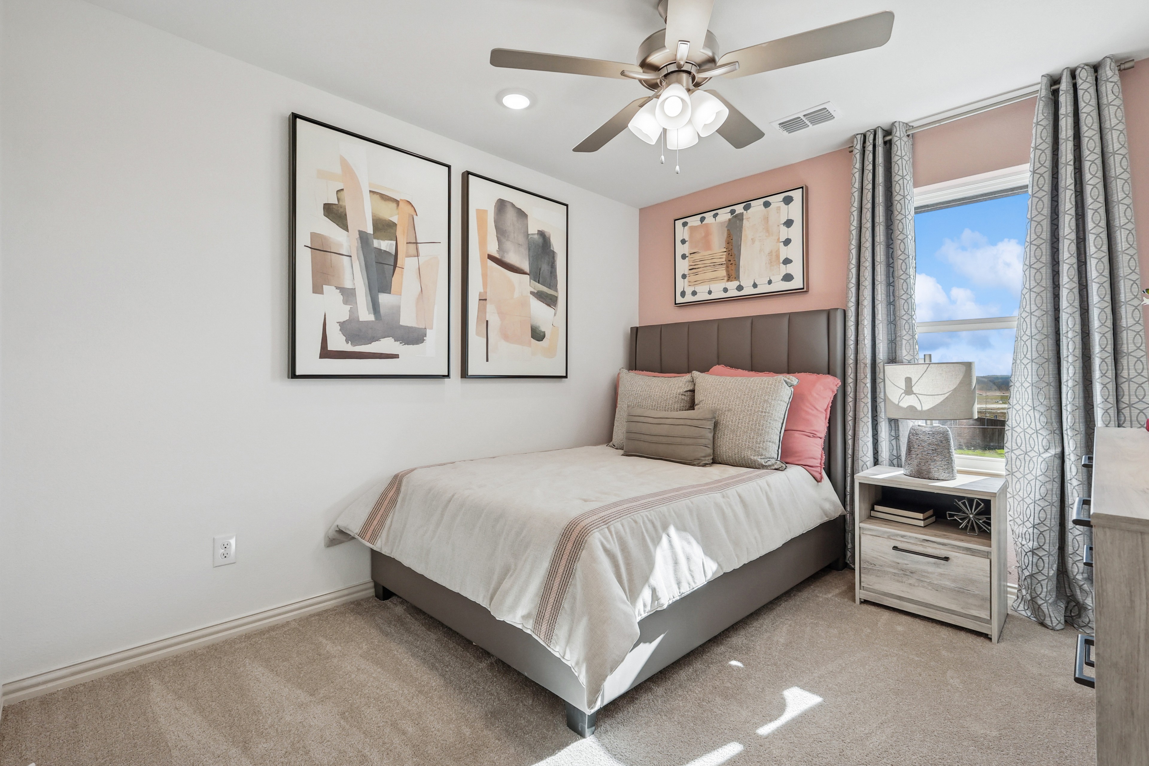 Elegant bedroom with abstract art, plush bed, modern fan, and window view in Bel Air Village home.