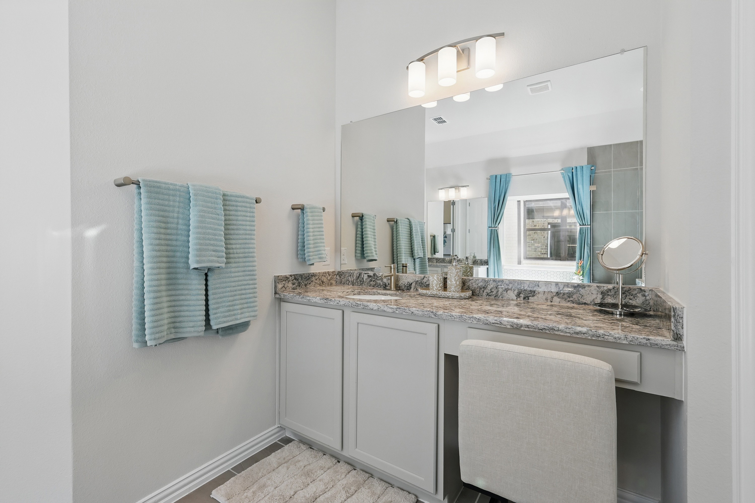 Elegant double vanity with marble countertop, large mirror, and modern light fixtures in Green Oaks Preserve.