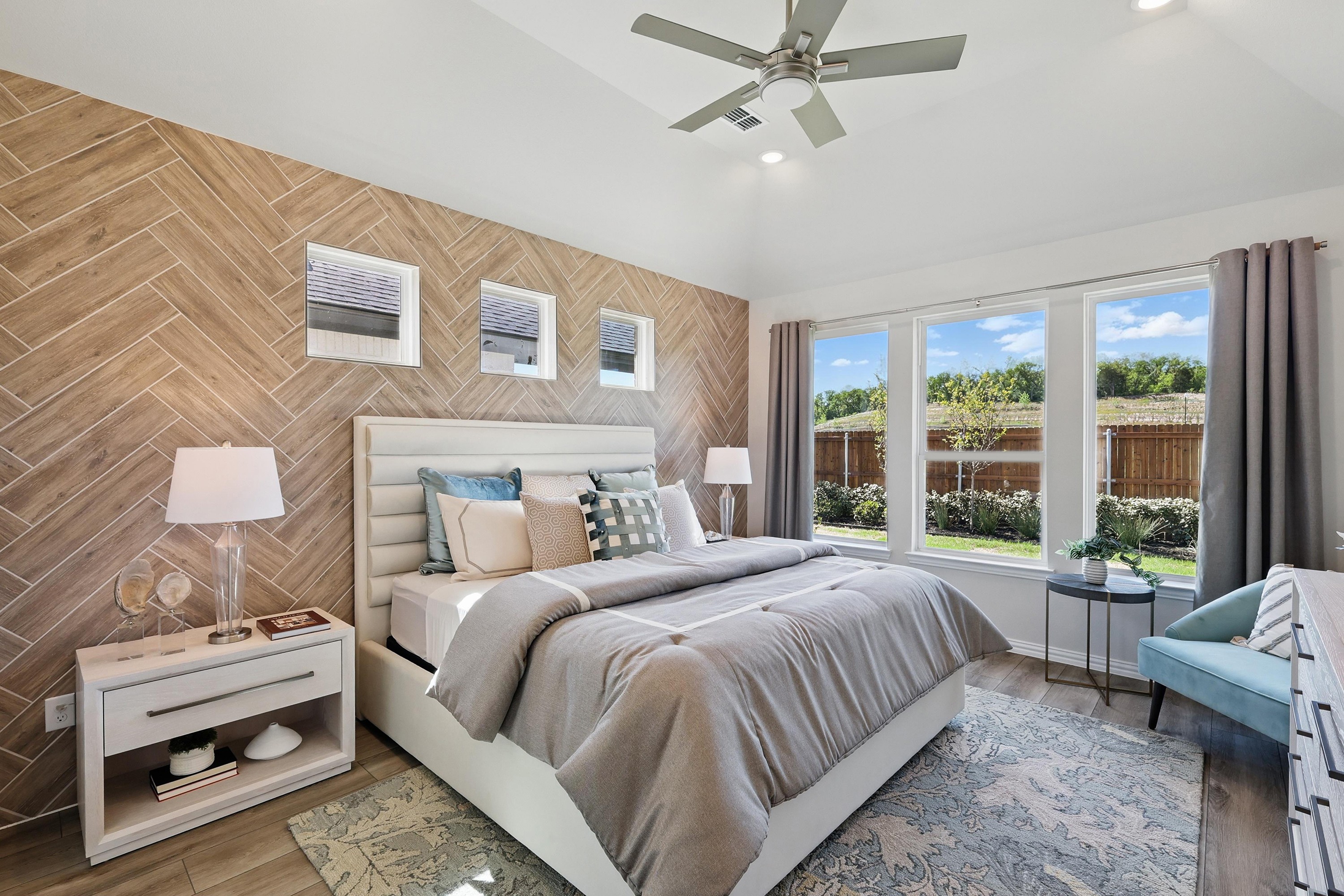 Luxurious bedroom with wood herringbone accent wall, large windows, elegant bed, Green Oaks Preserve.