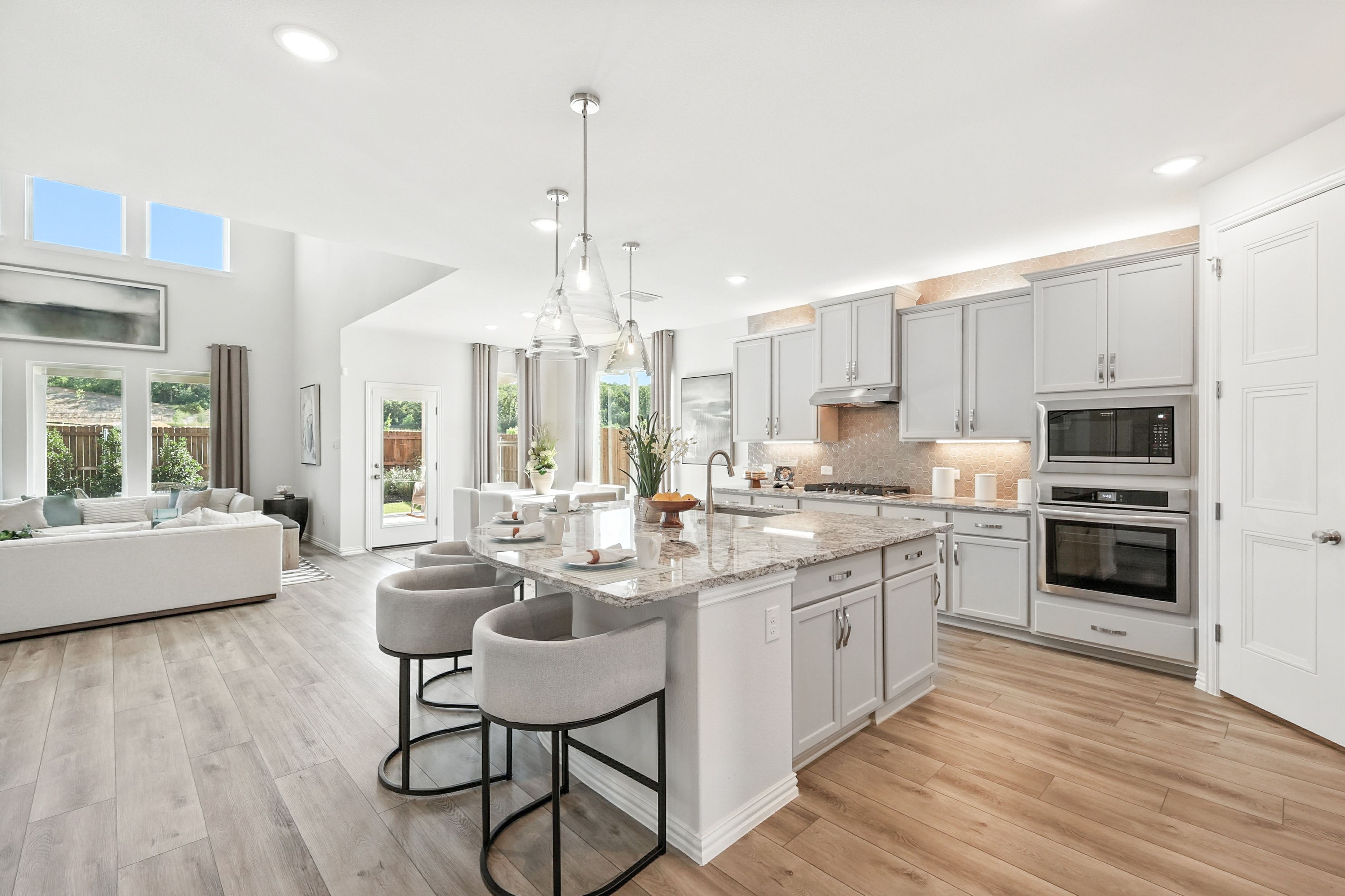 Modern kitchen with granite island, pendant lights, and gray cabinets in Green Oaks Preserve, spacious and bright.